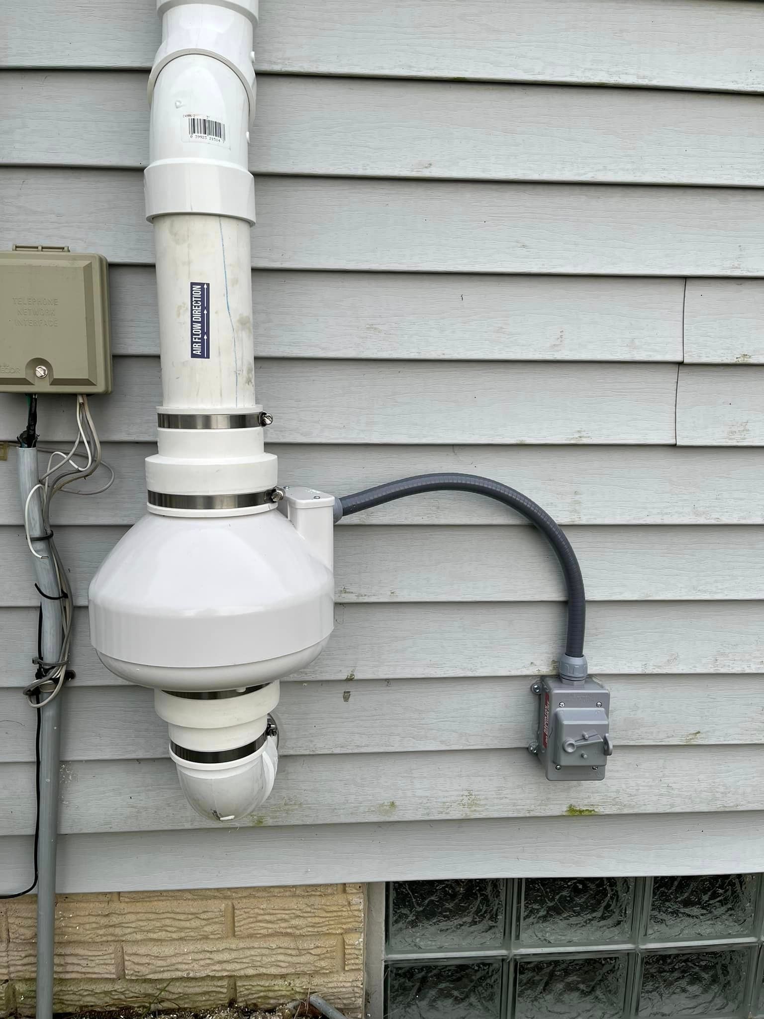 A white pipe is attached to the side of a house
