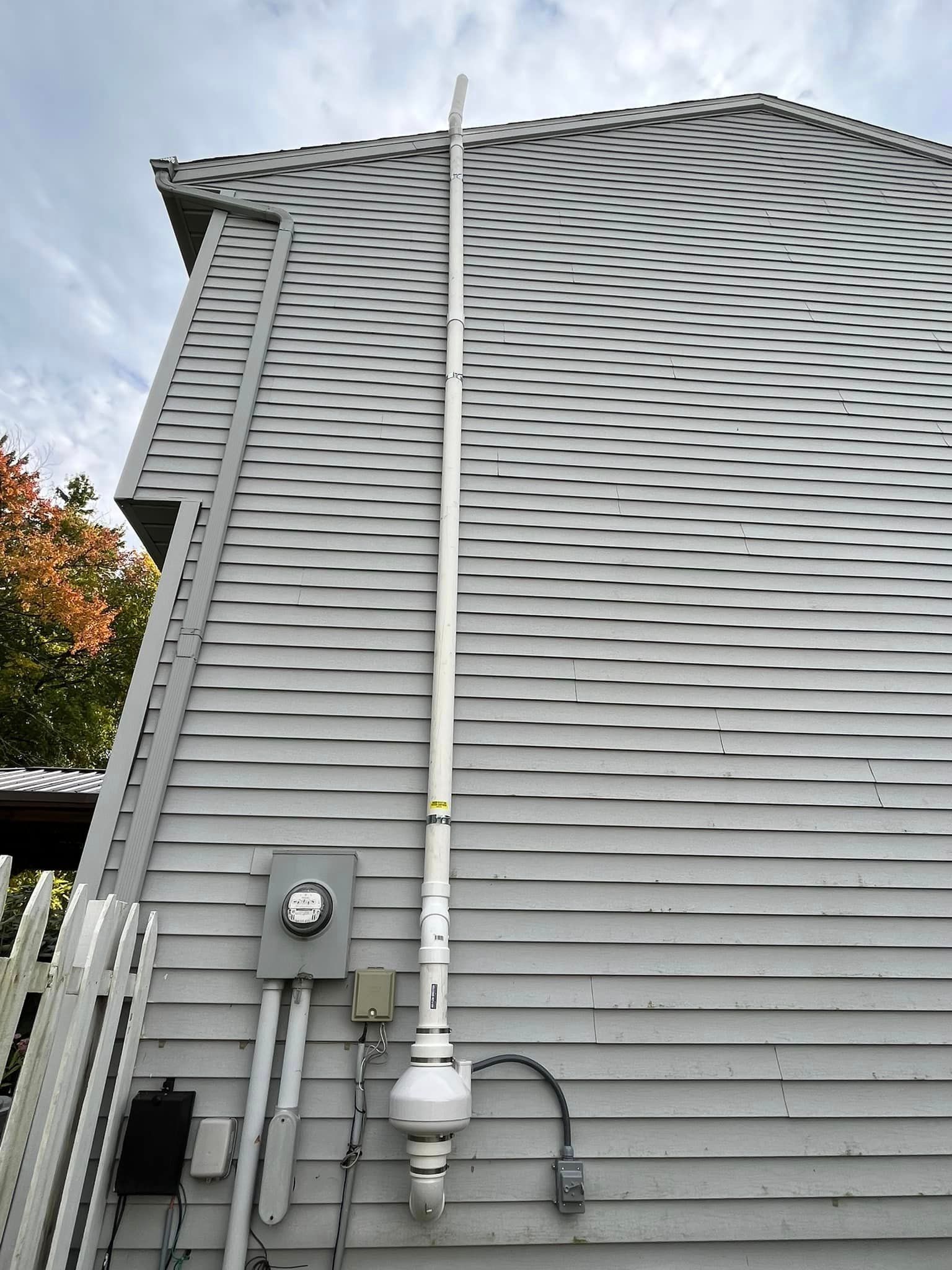 A white pipe is attached to the side of a house.