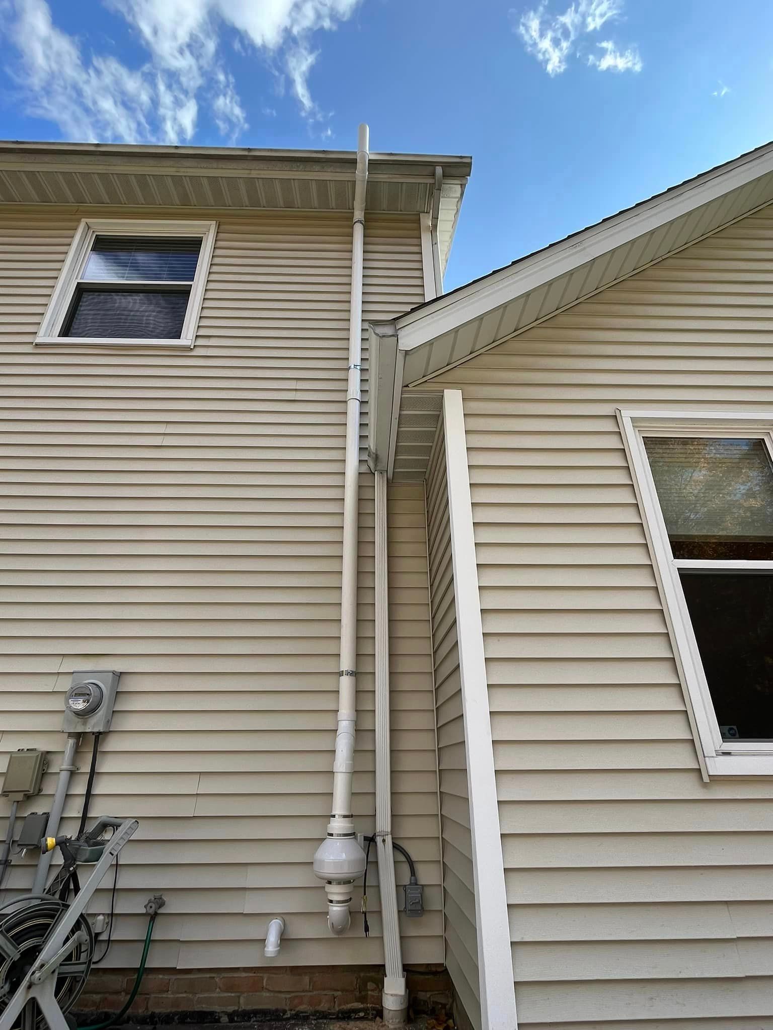 A house with a white siding and a white pipe on the side of it.