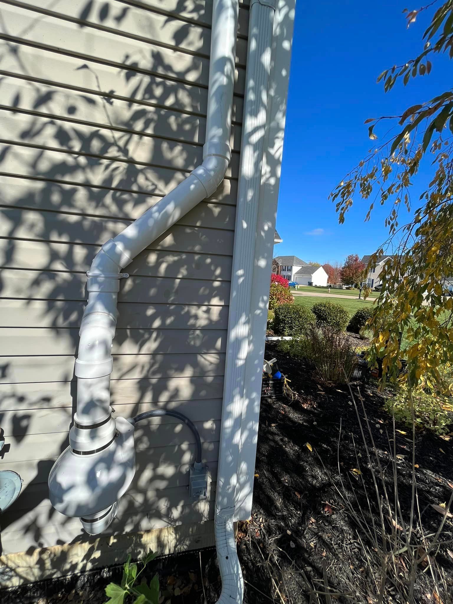 A white pipe is attached to the side of a house.