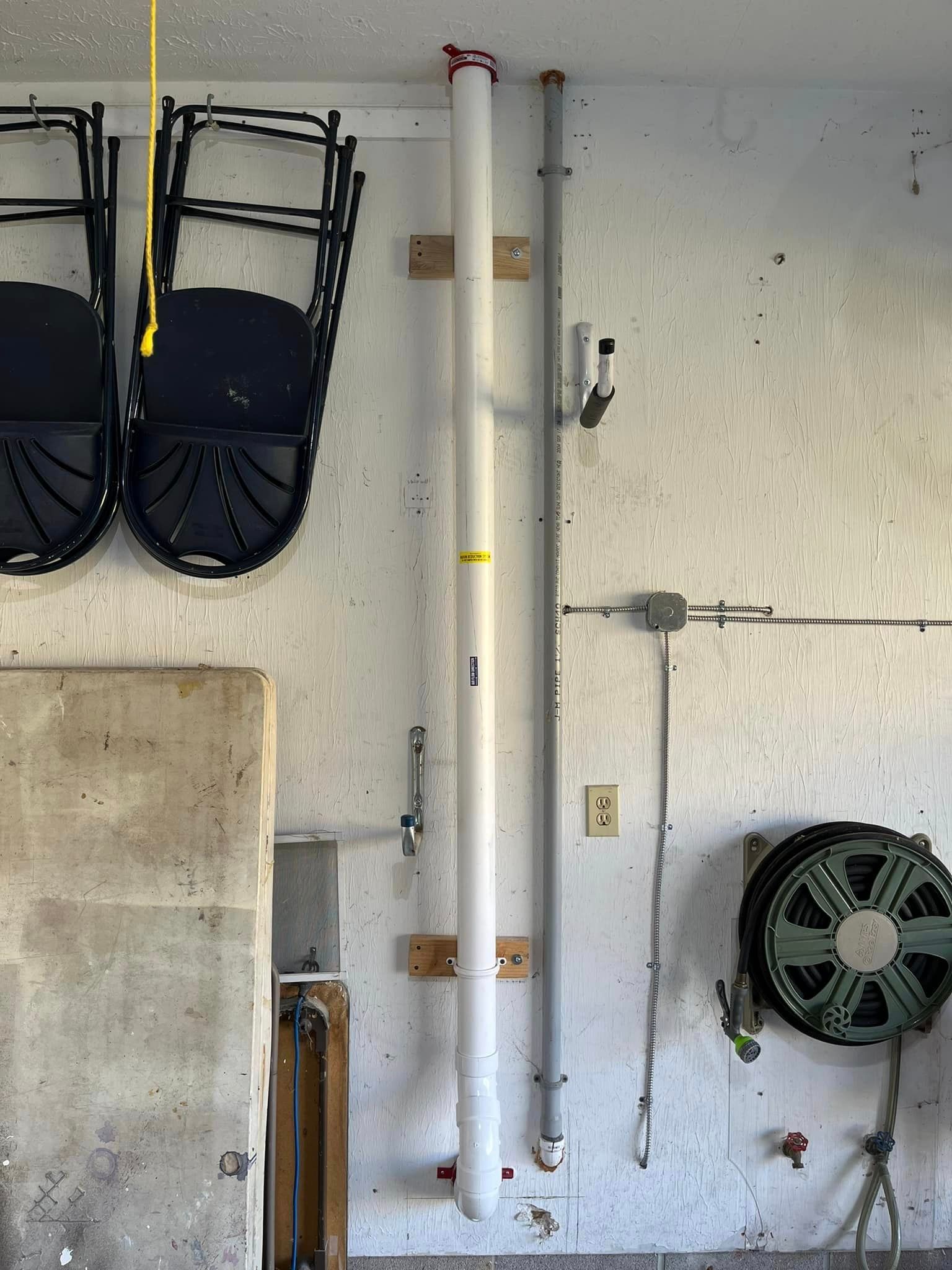 A white pipe is hanging from the ceiling of a garage.