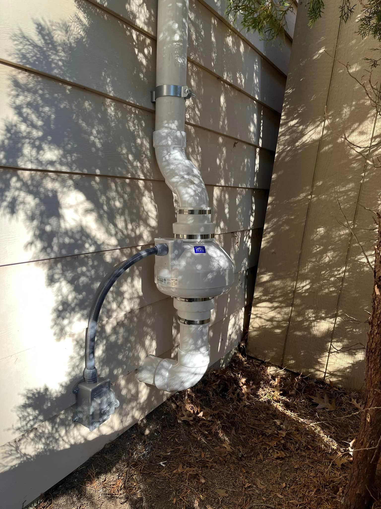A white pipe is attached to the side of a house.