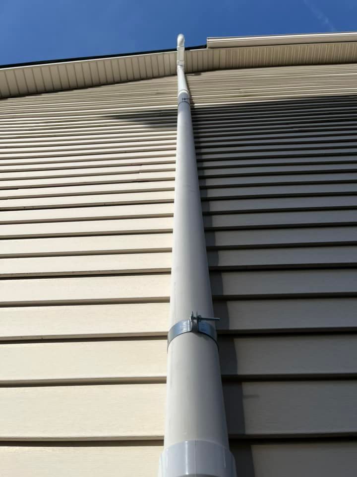 A white pipe is attached to the side of a house