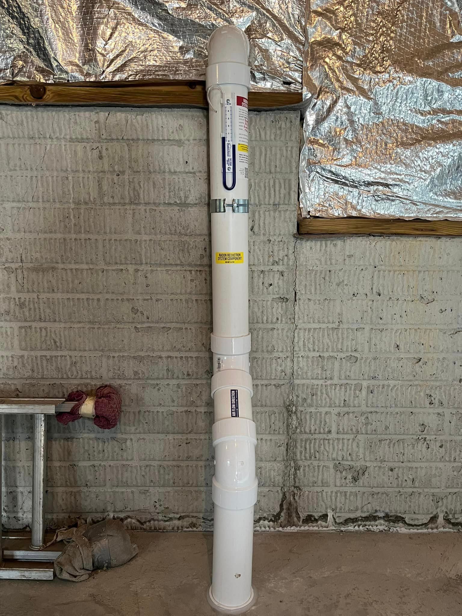 A large white rocket is sitting in a room next to a brick wall.
