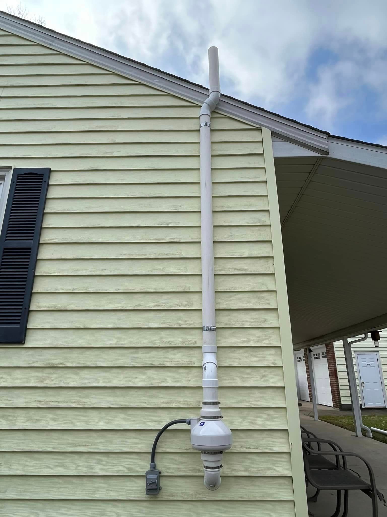 A white pipe is attached to the side of a house.