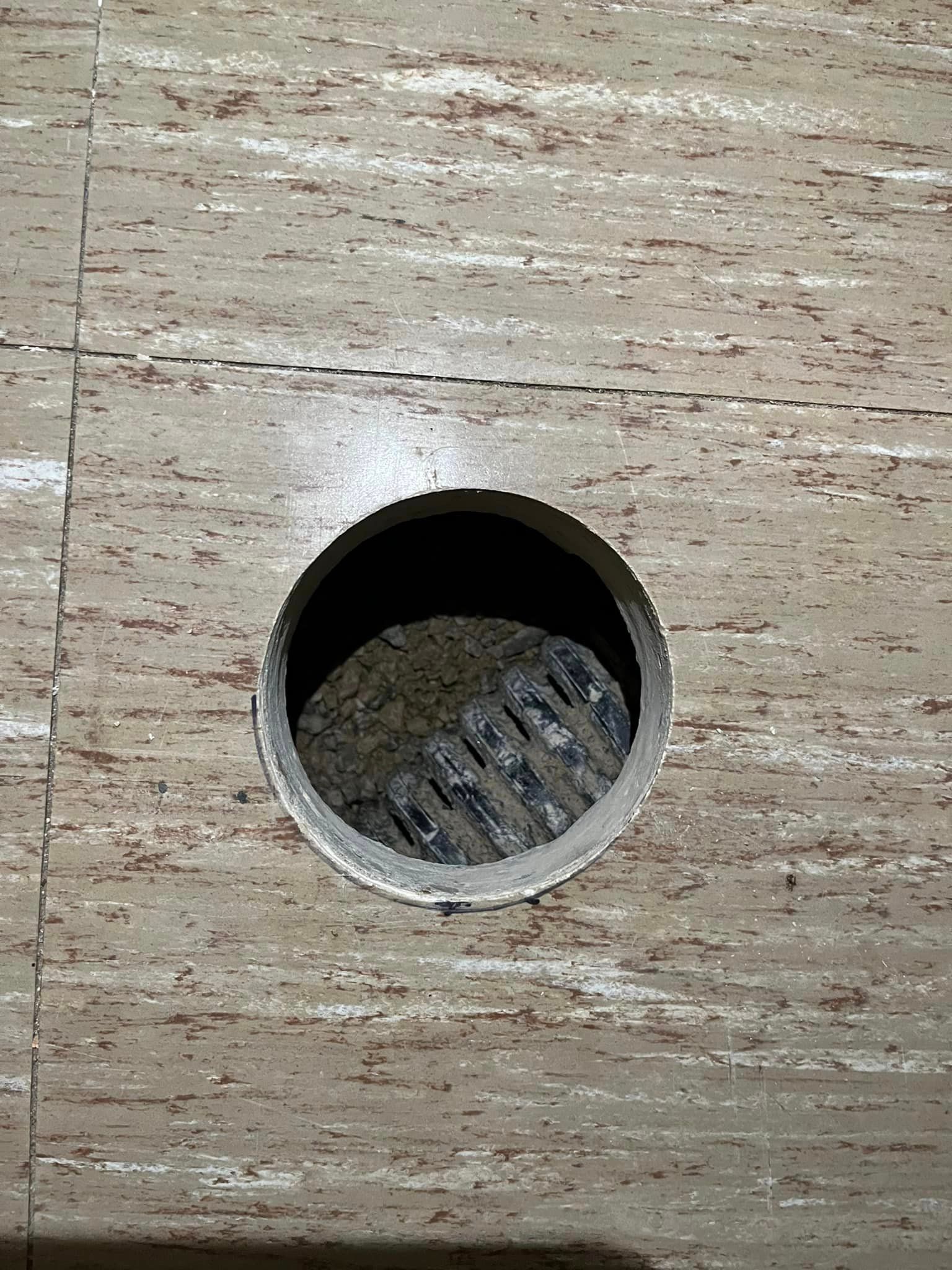 A hole in a wall with a drain in it.