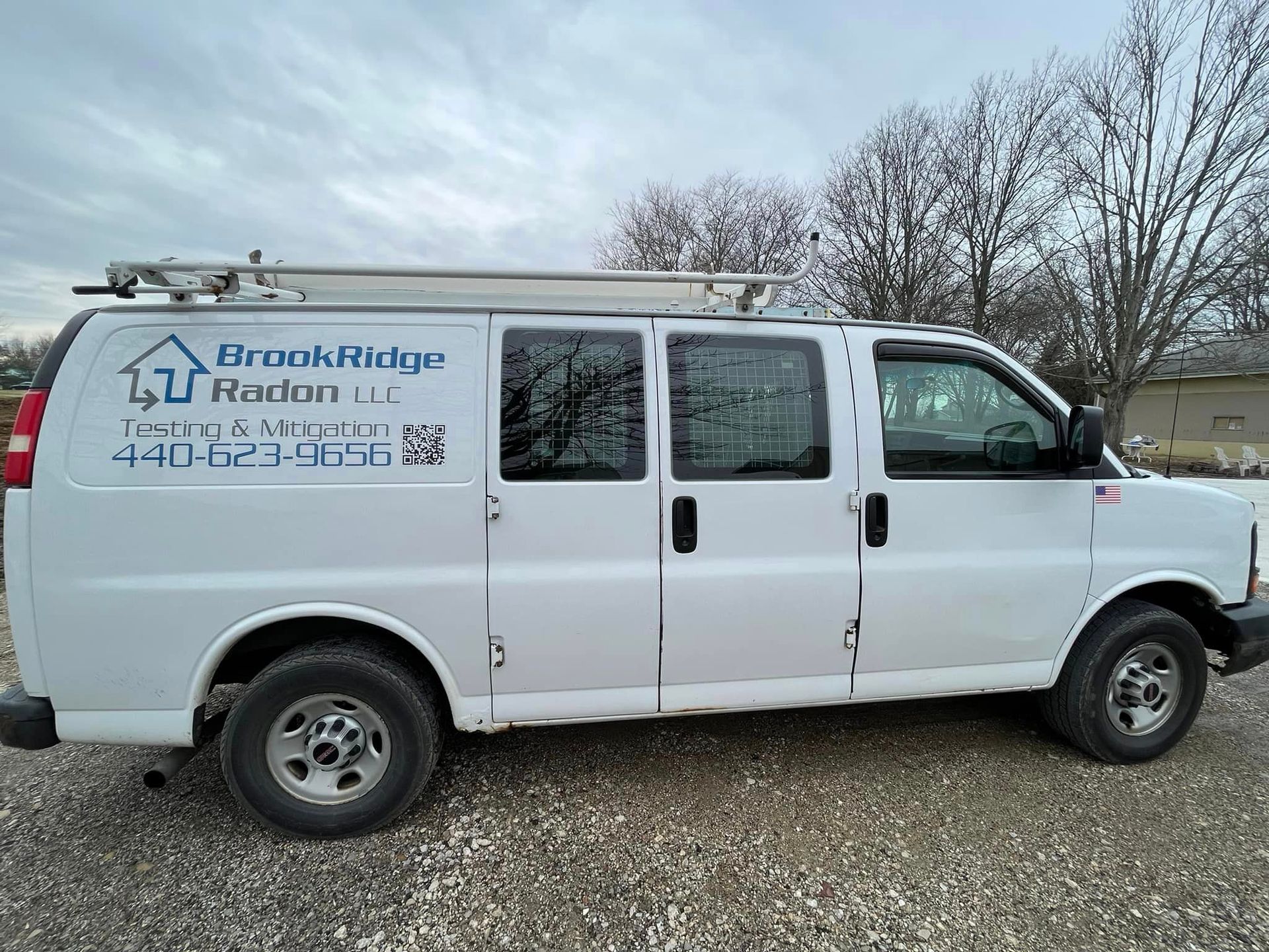 A white van is parked in a gravel lot.