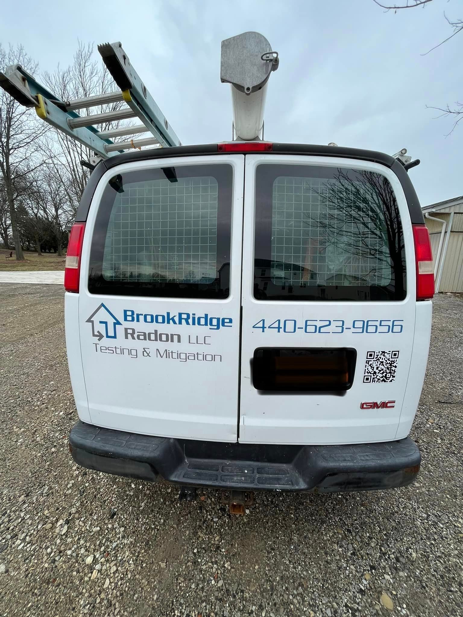 The back of a white van with a ladder on top of it.