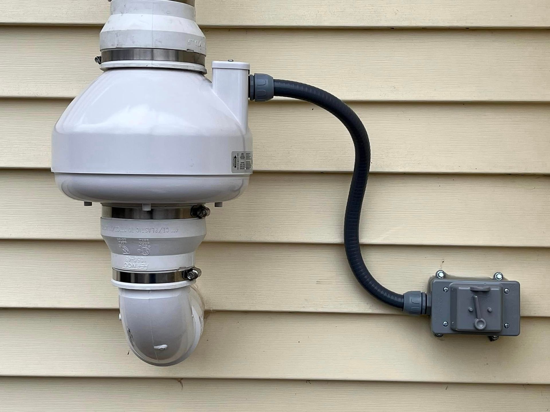 A white pipe is attached to the side of a house.