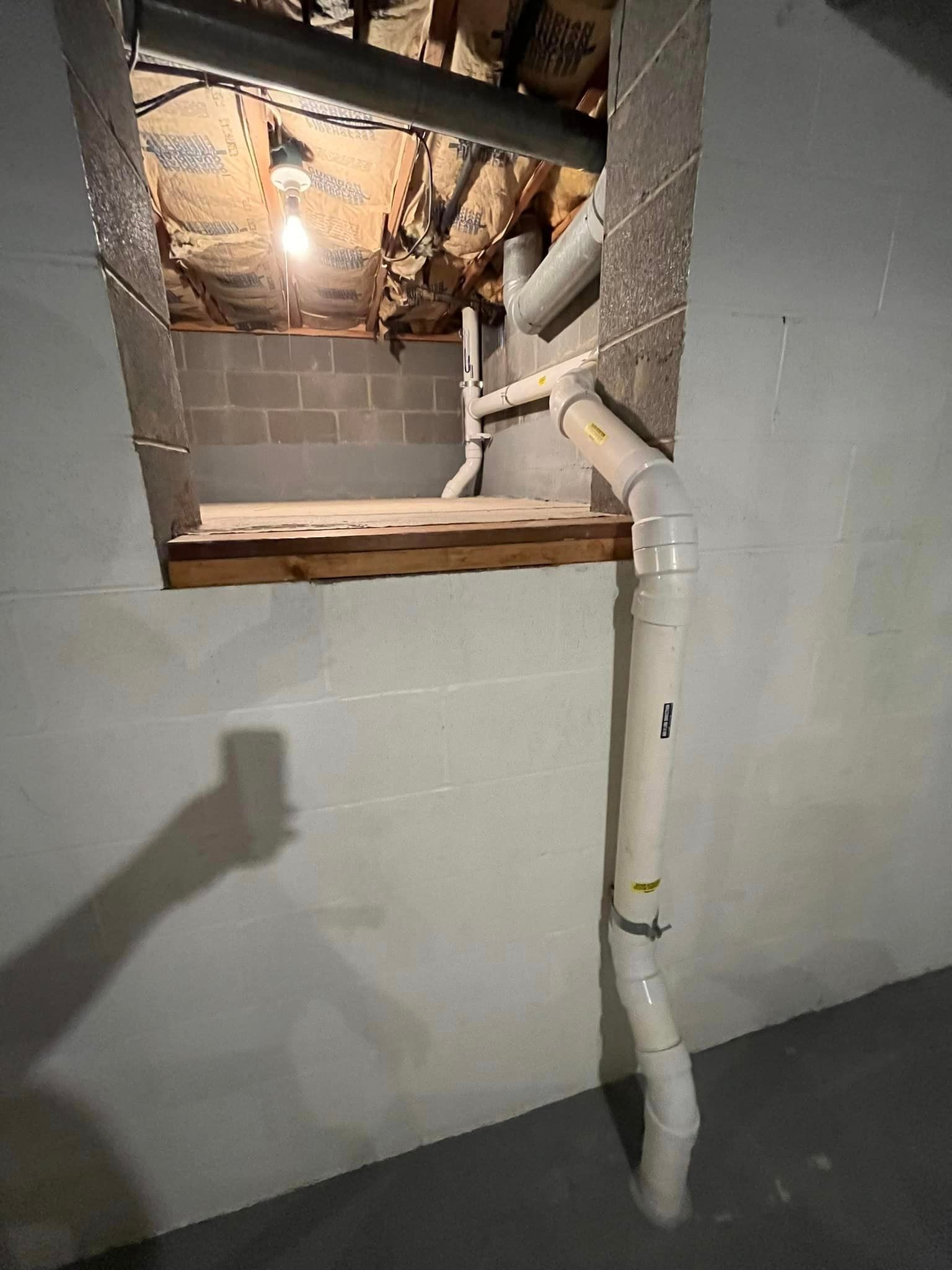 A basement with a window and pipes coming out of it.