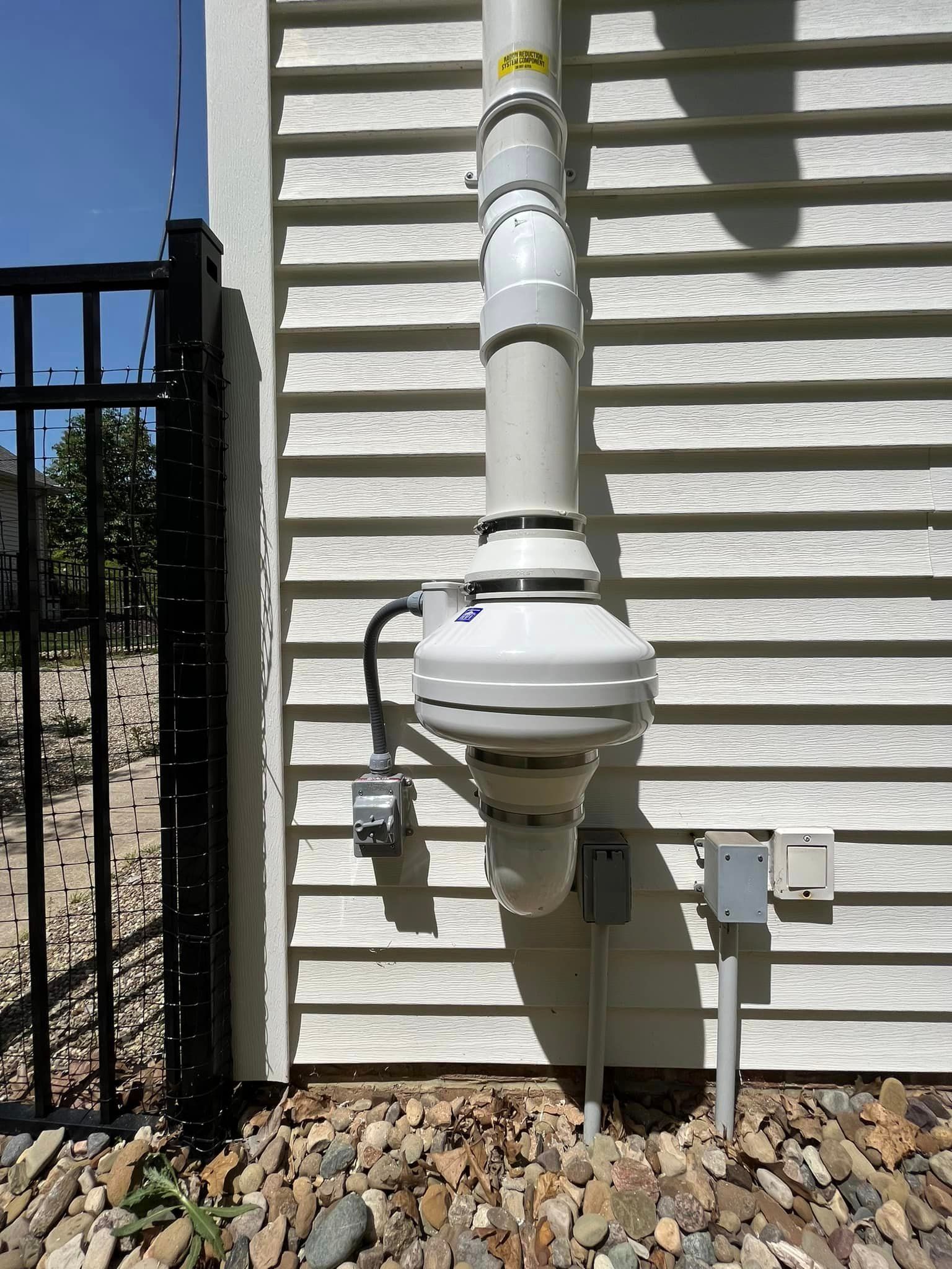 A white pipe is attached to the side of a house.