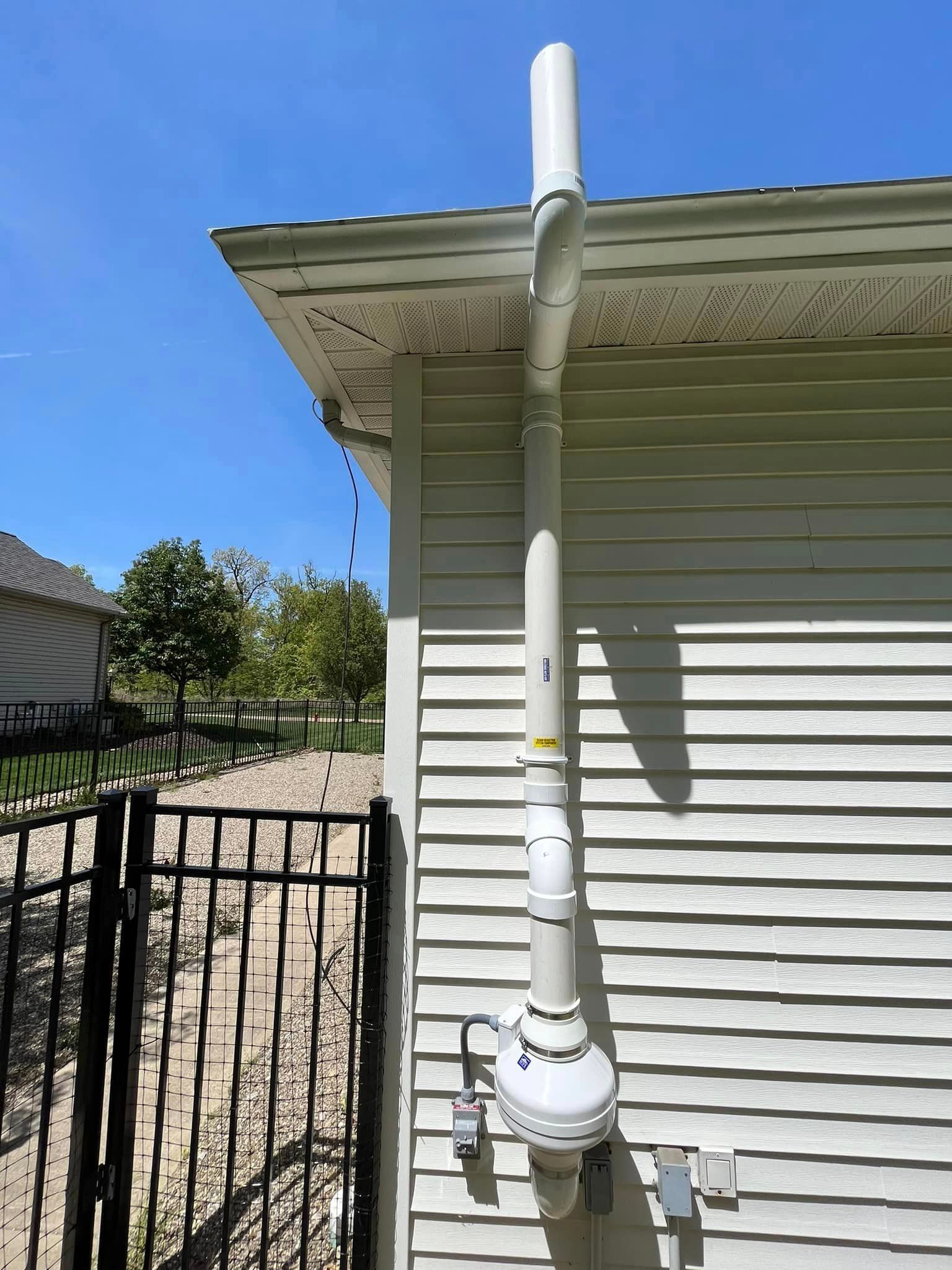 A white pipe is attached to the side of a house.