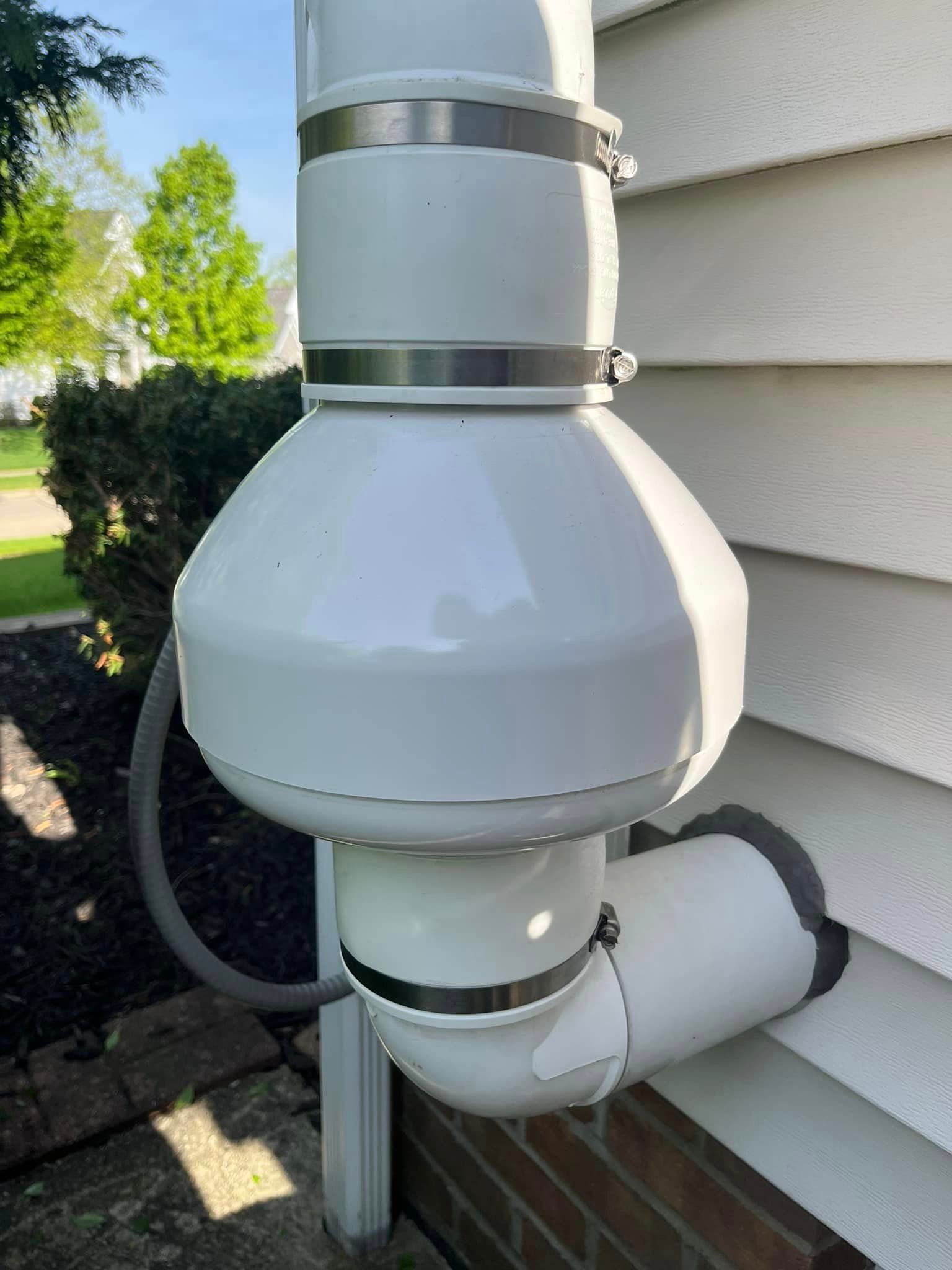 A white pipe is attached to the side of a house.