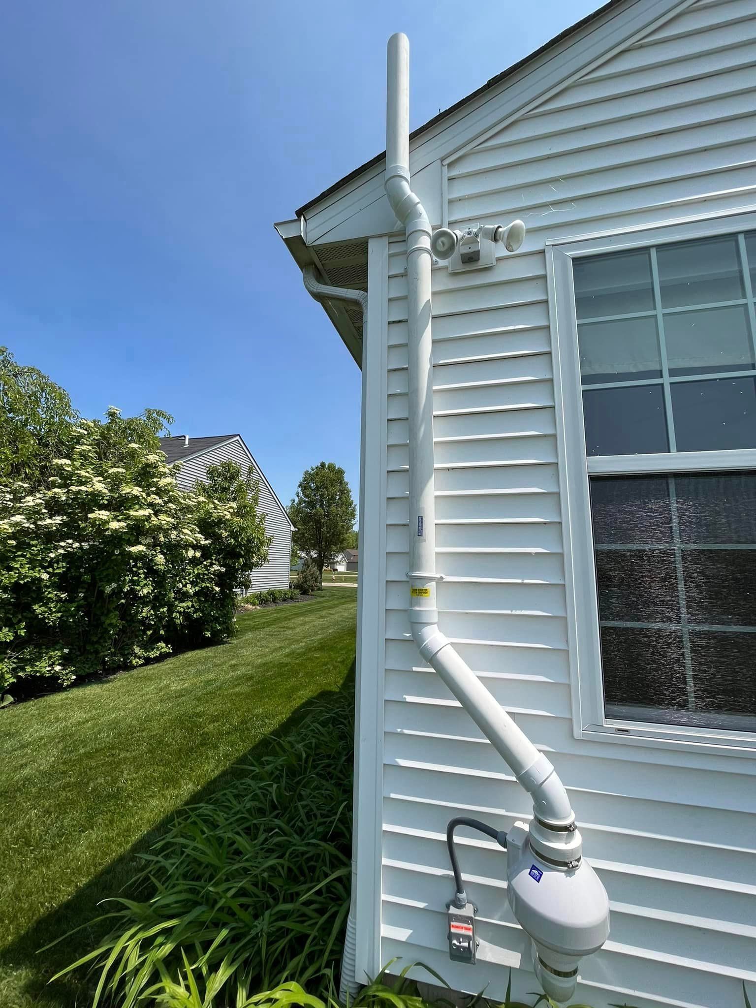A white house with a drain pipe attached to the side of it.