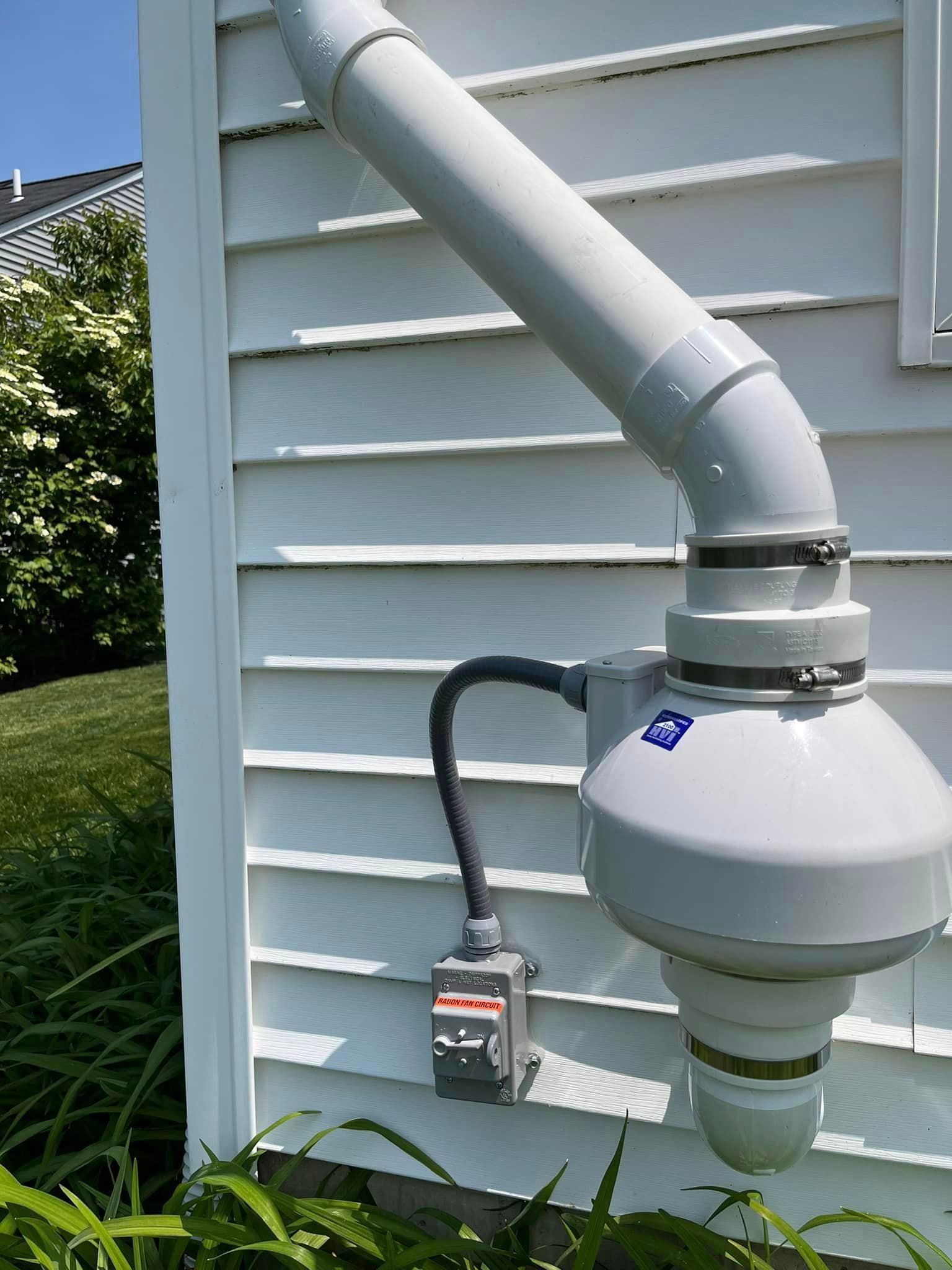 A white pipe is attached to the side of a house.