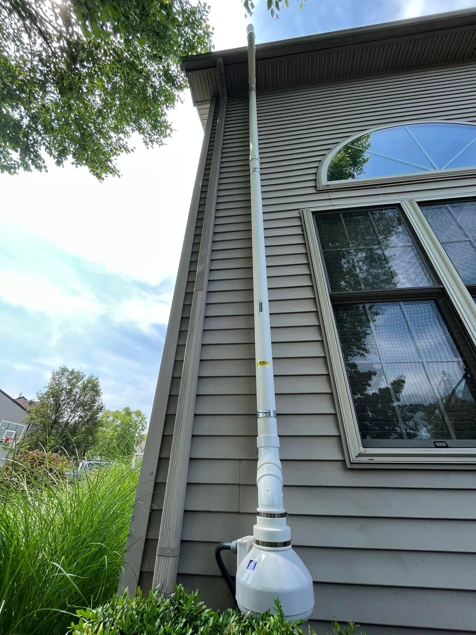 A white pipe is attached to the side of a house.