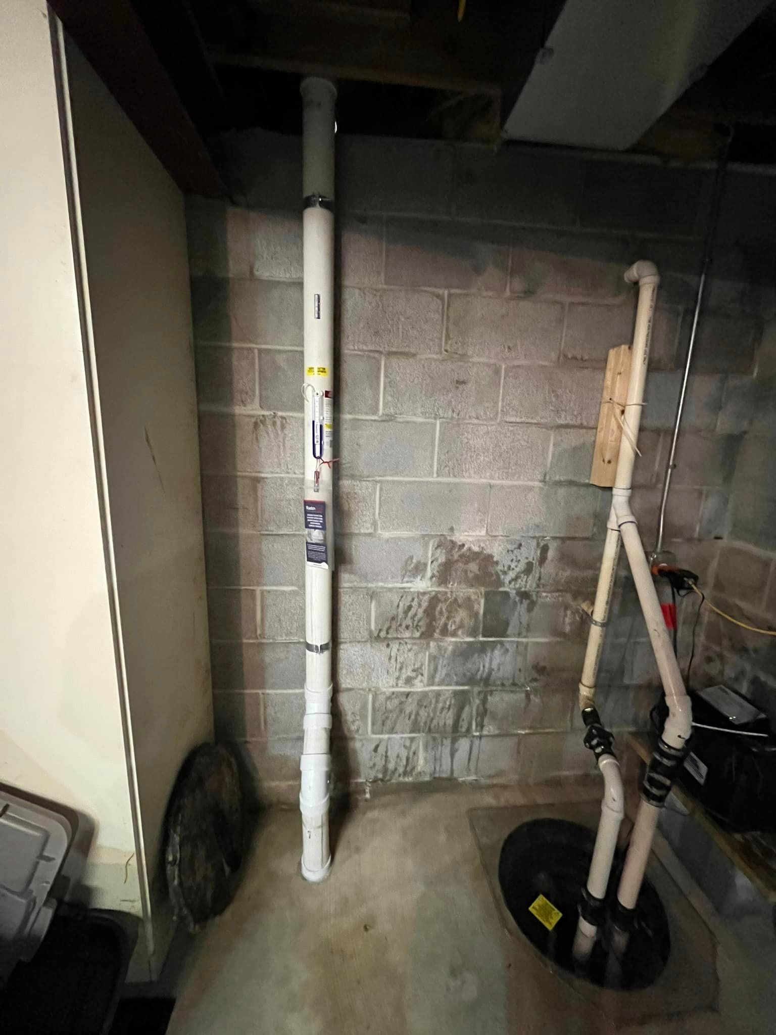 A basement with a brick wall and a drain pipe.