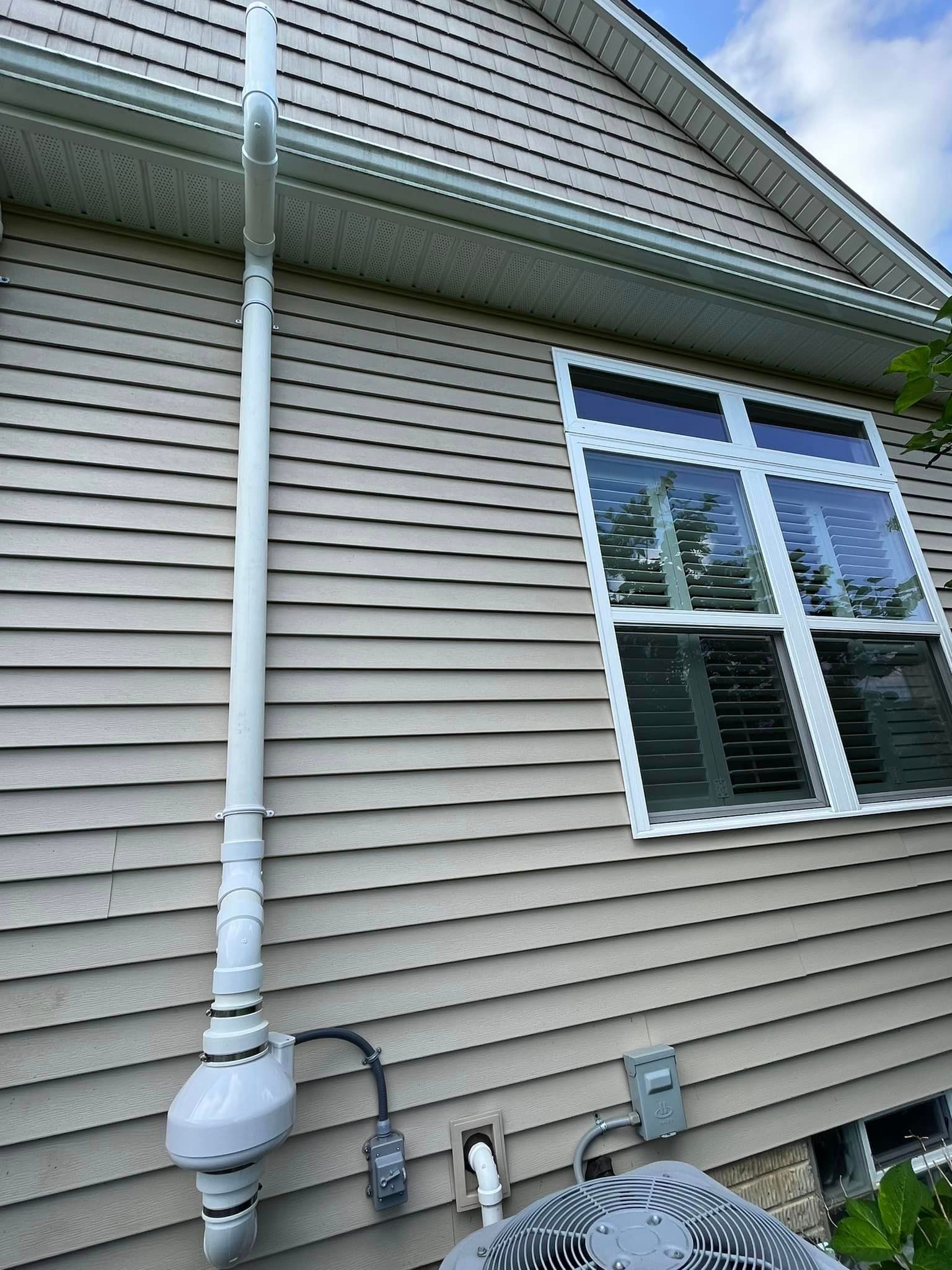 A house with a window and a drain pipe on the side of it.