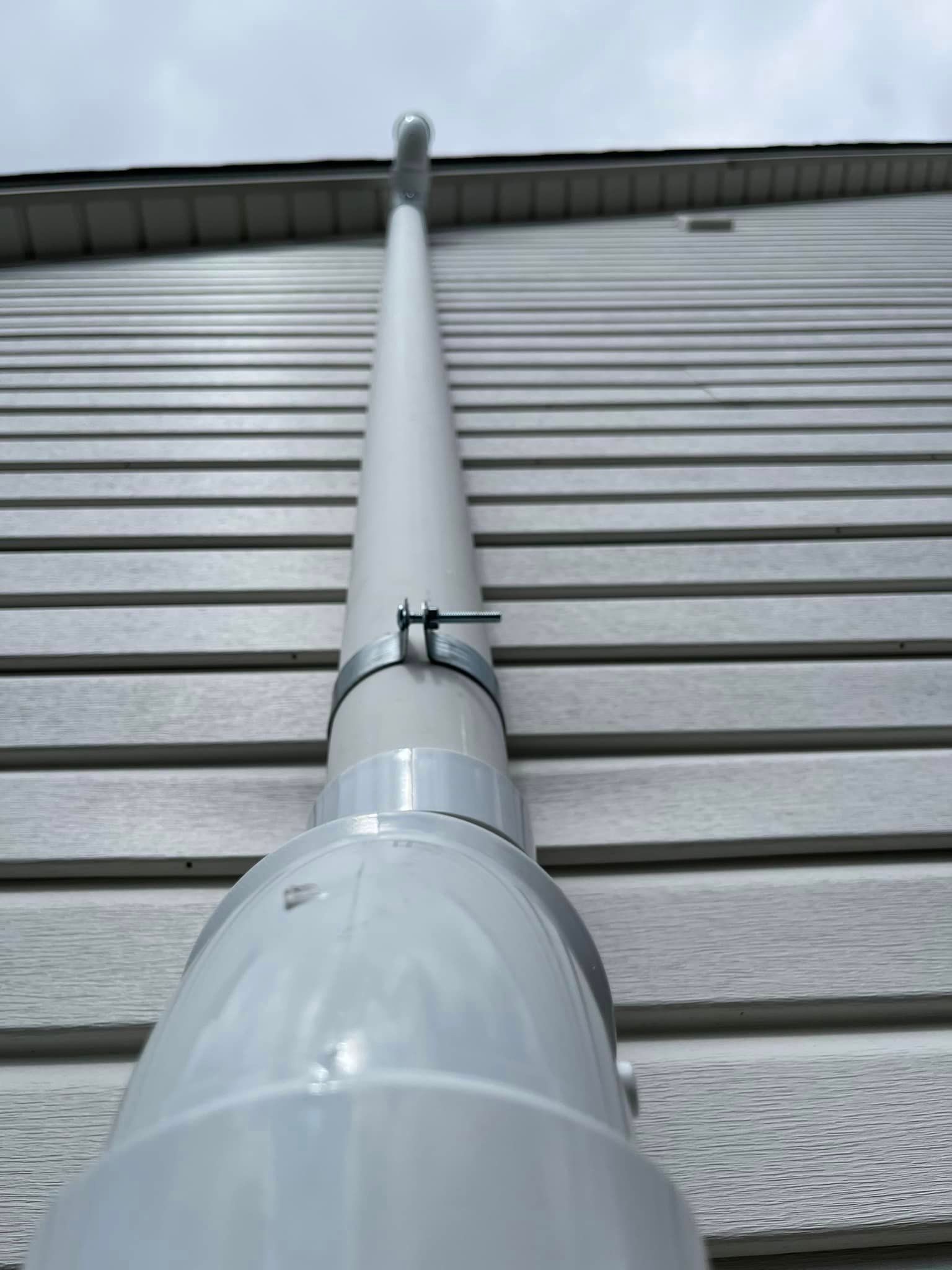 A white pipe is attached to the side of a house.