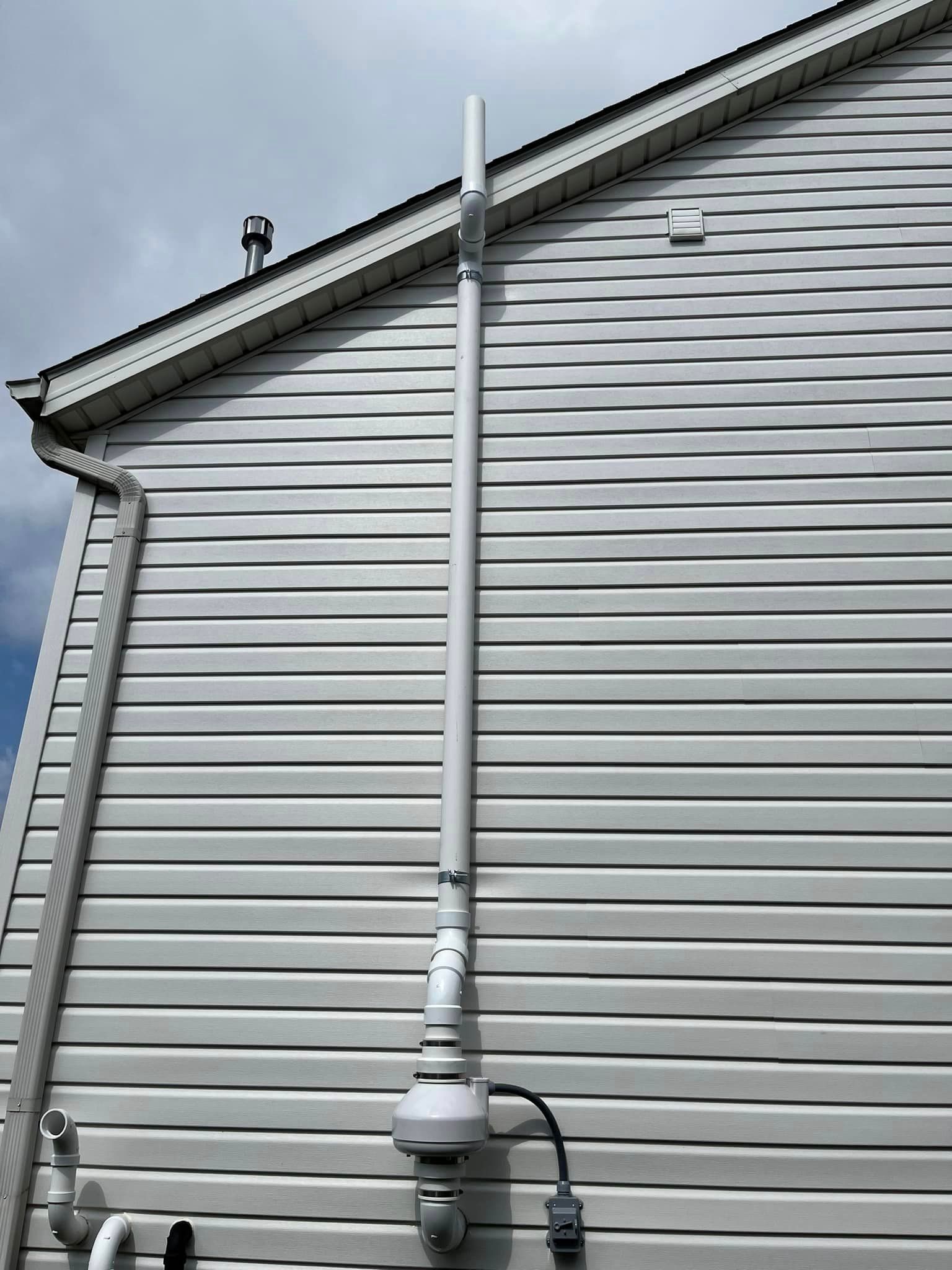 A white house with a white pipe attached to the side of it.