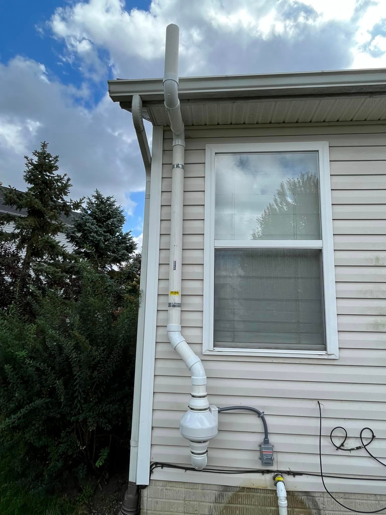A white house with a drain pipe attached to the side of it