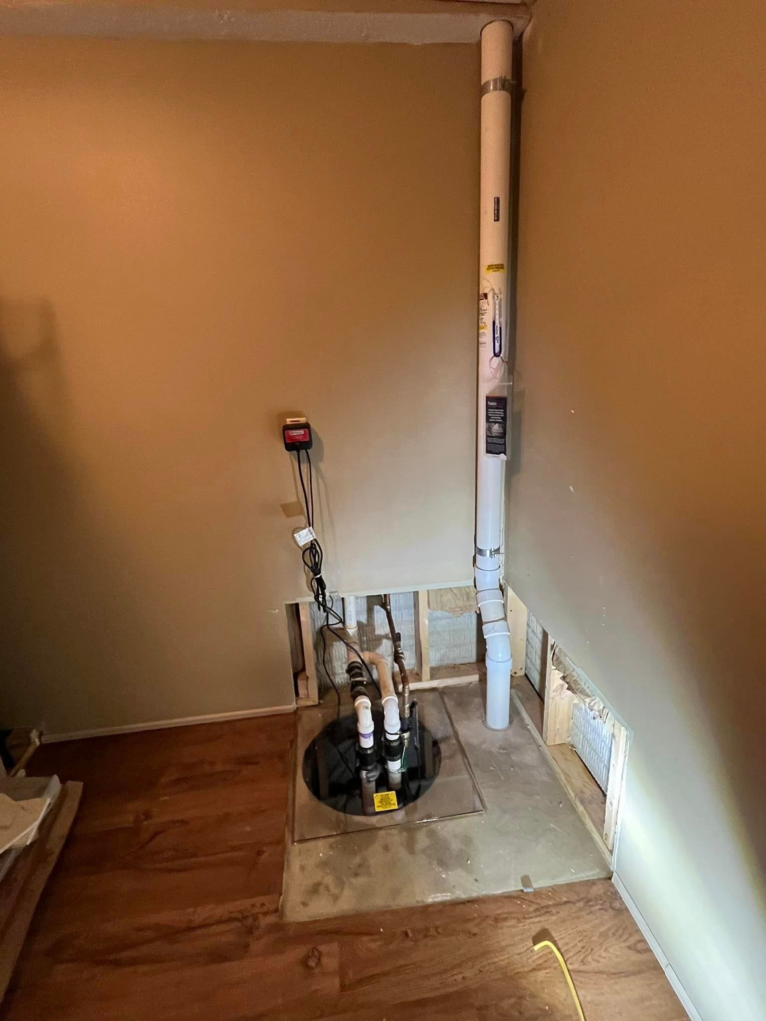A room with a basement pump and a pipe in it.
