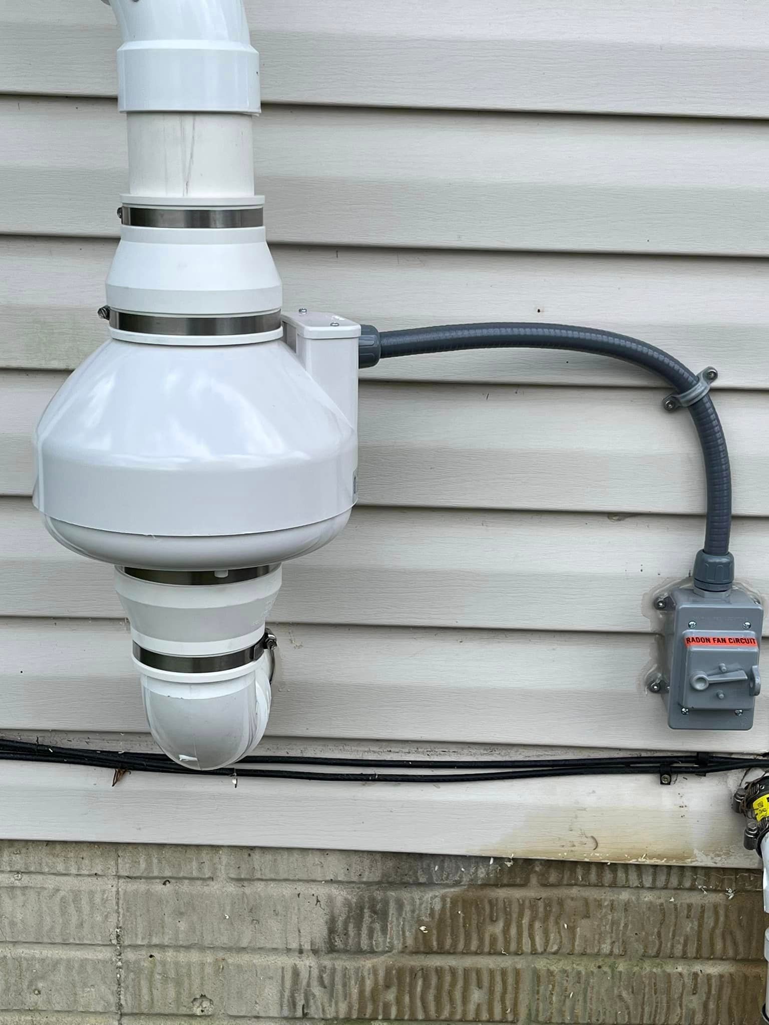 A white pipe is attached to the side of a house.