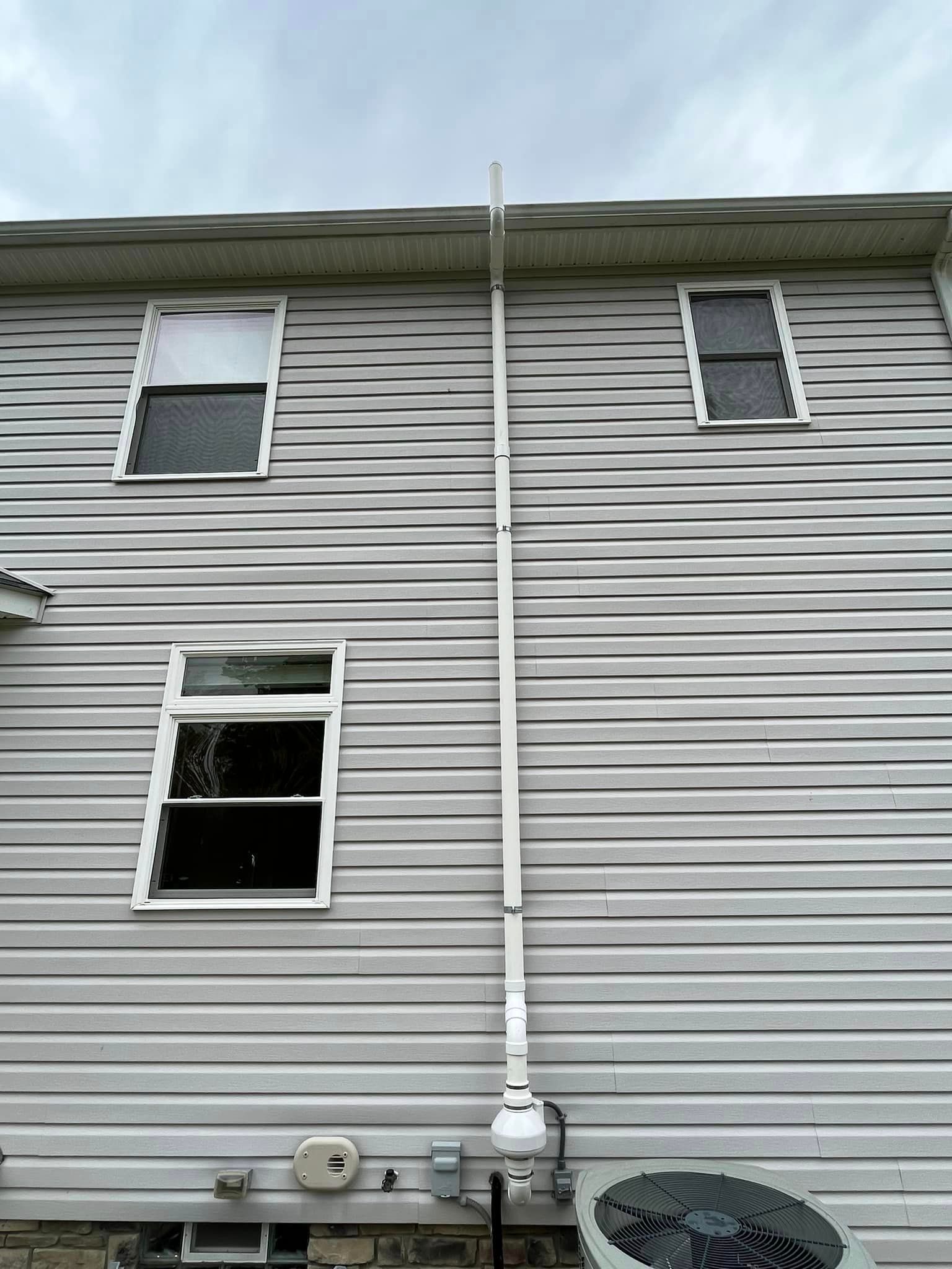 The back of a house with a drain pipe attached to it.