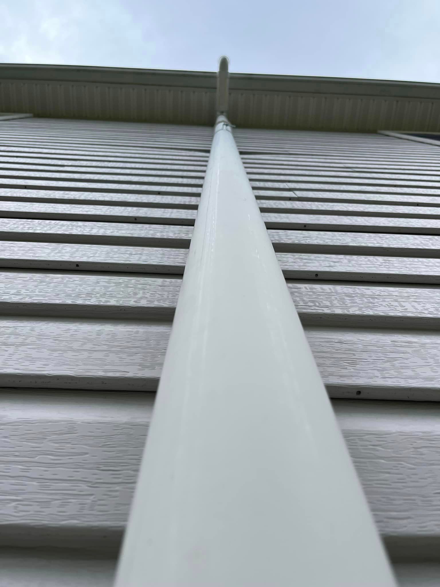 A close up of a white pipe on the side of a house.