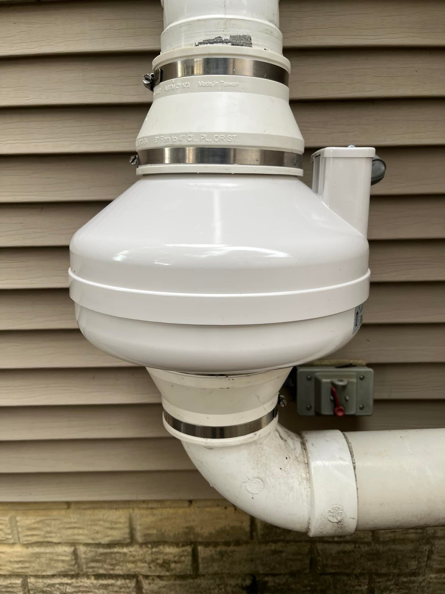 A white pipe is attached to the side of a house.