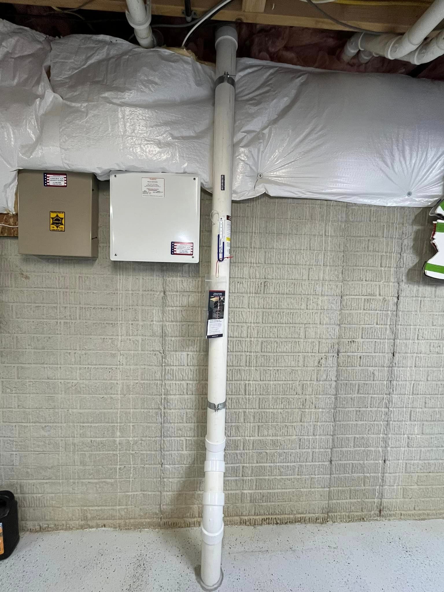 A white pipe is hanging from the ceiling in a basement.