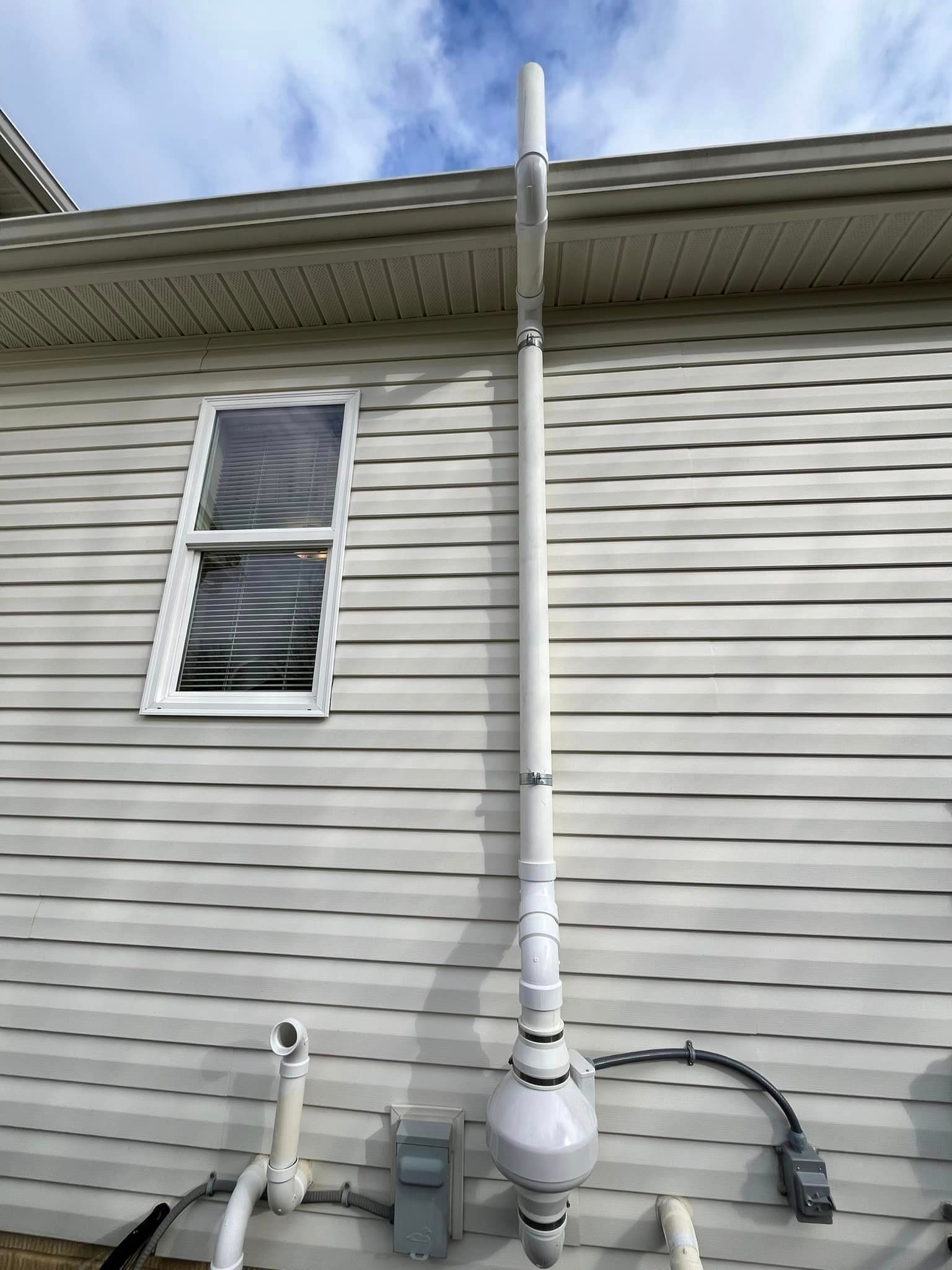 A white house with a white pipe attached to the side of it.
