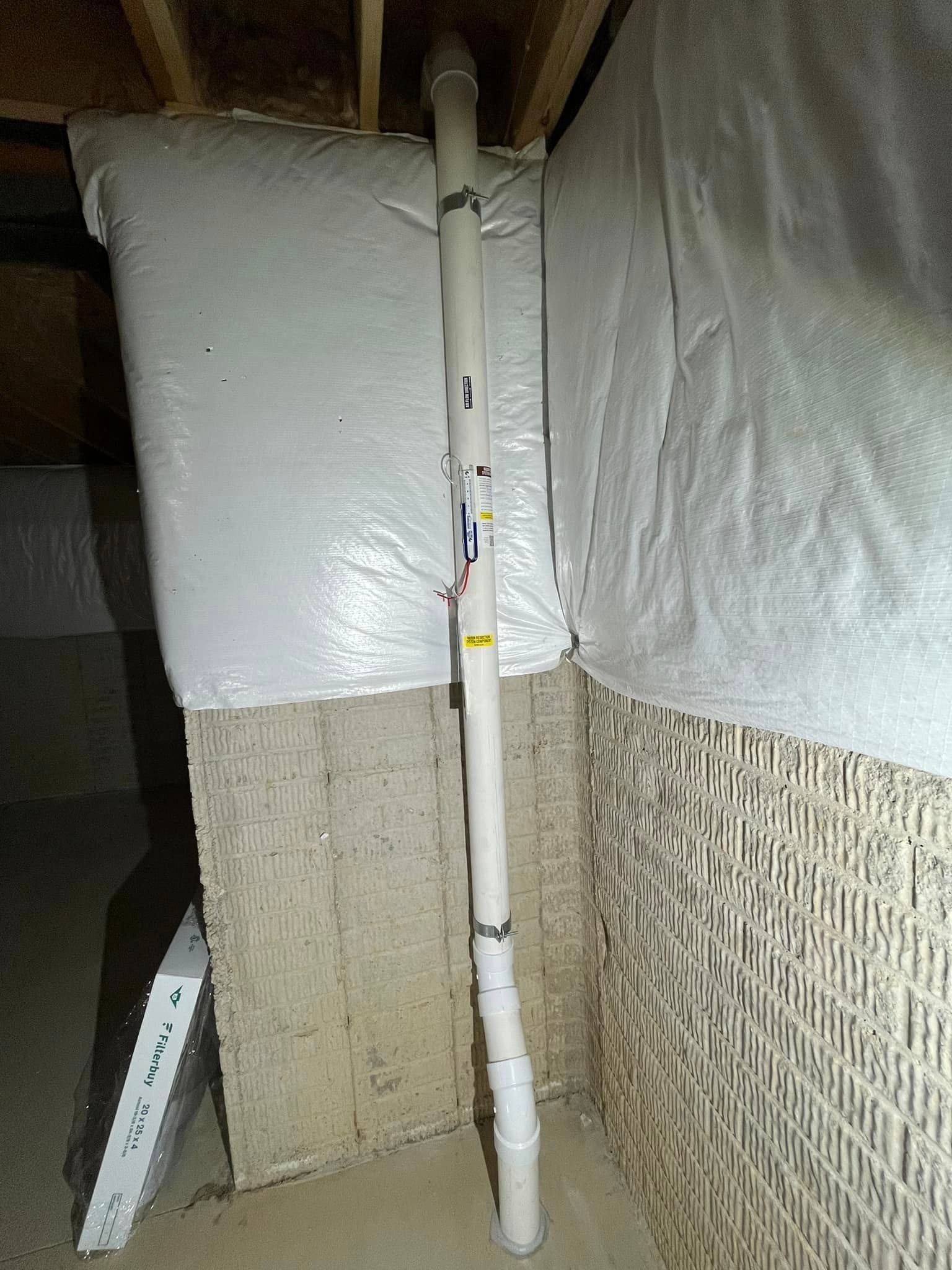 A white pipe is sitting in the corner of a basement.