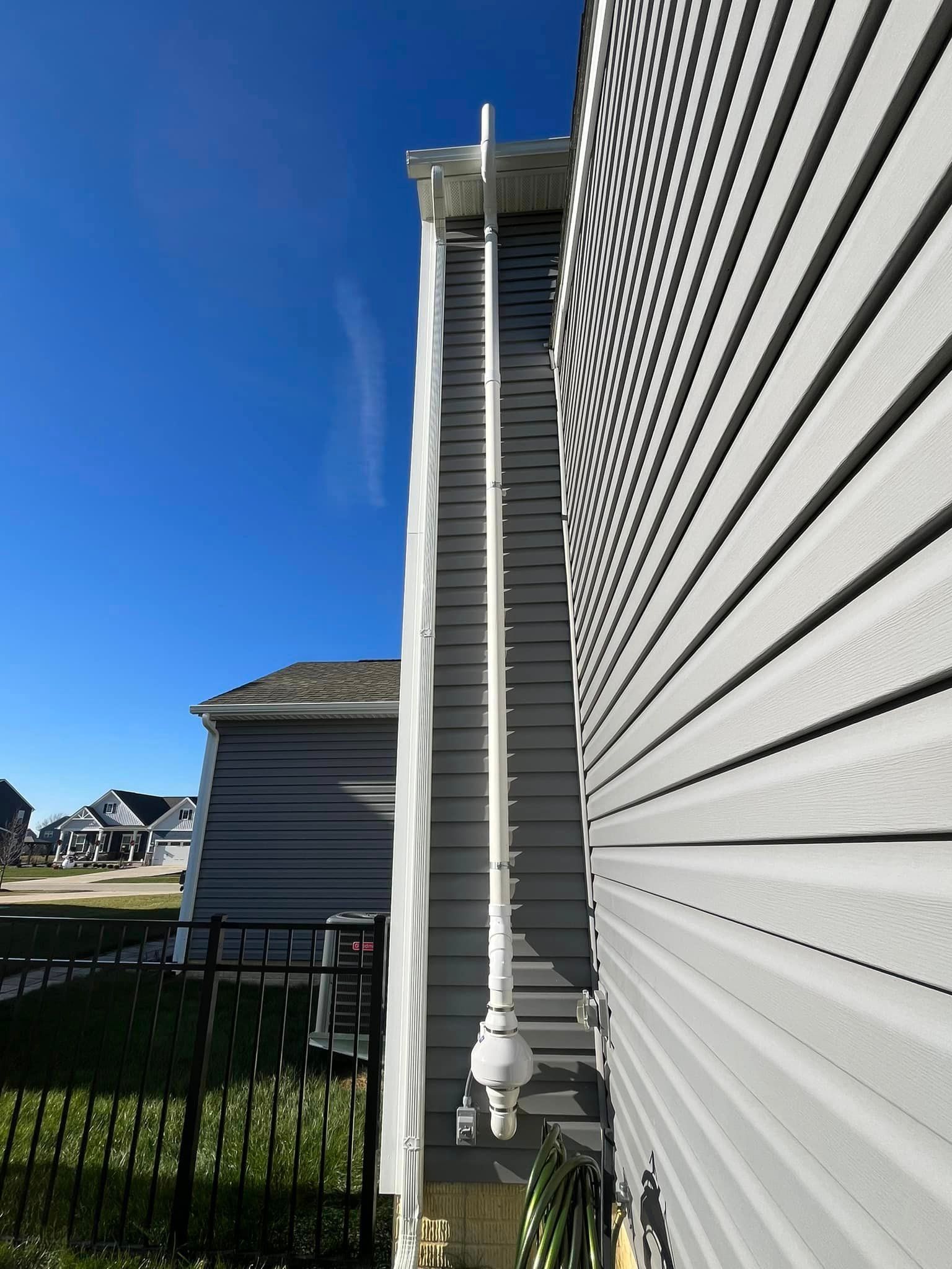 A white pipe is hanging from the side of a house.