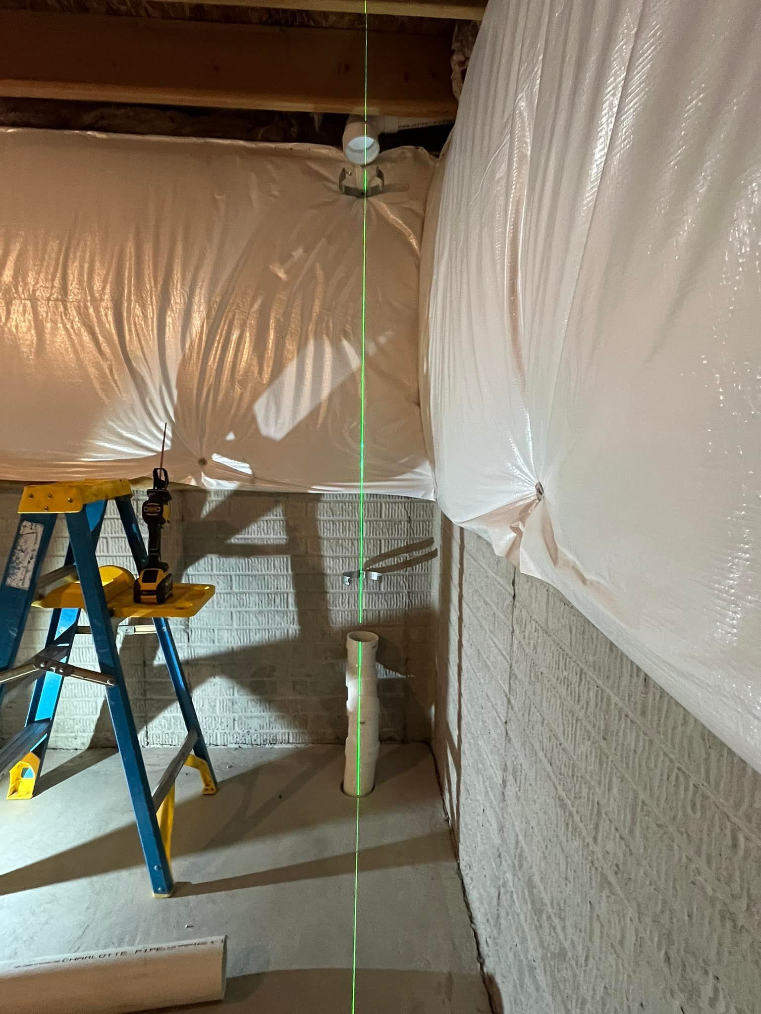 A person is using a laser level in a basement.