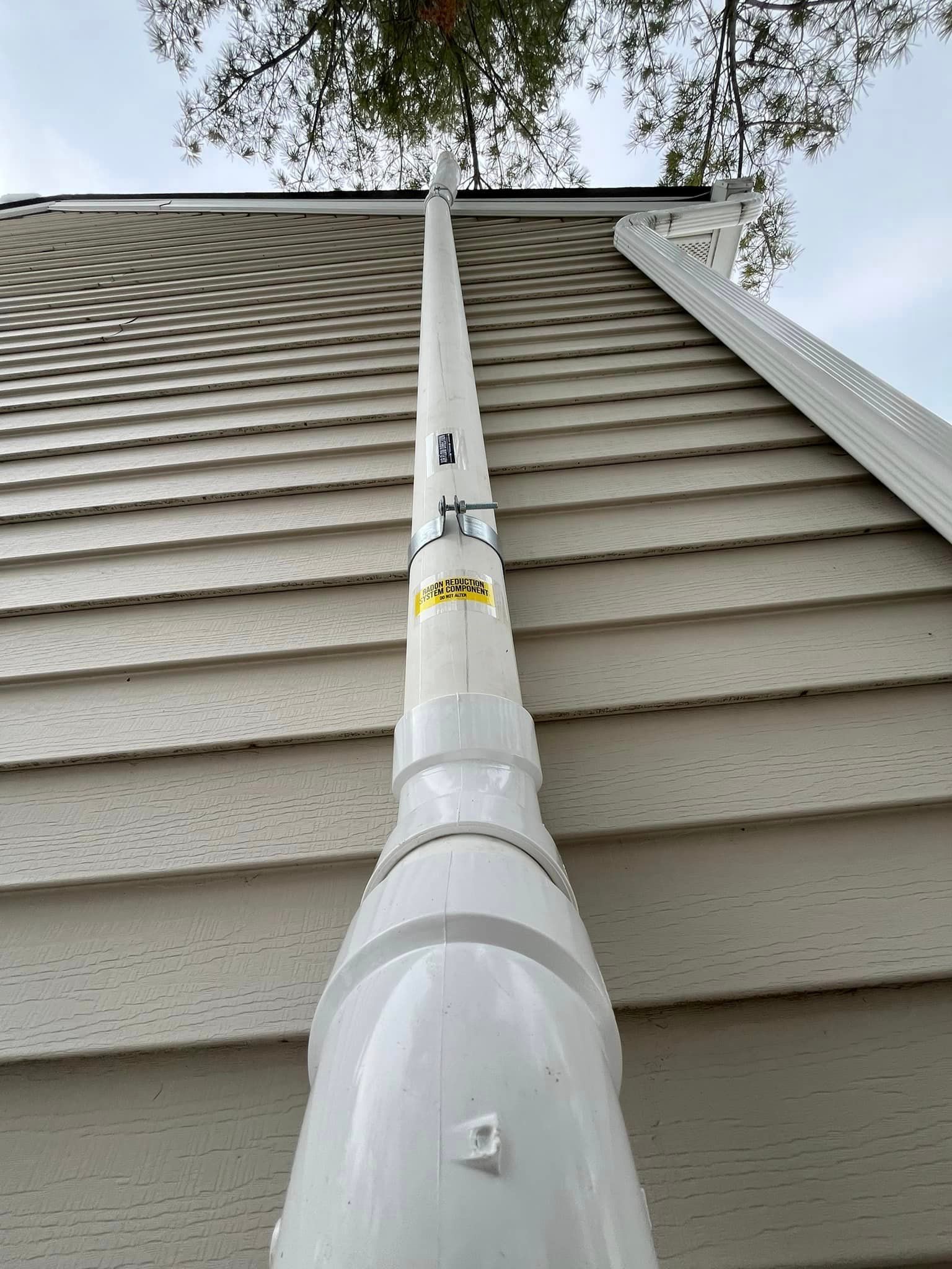 A white drainpipe is attached to the side of a house.