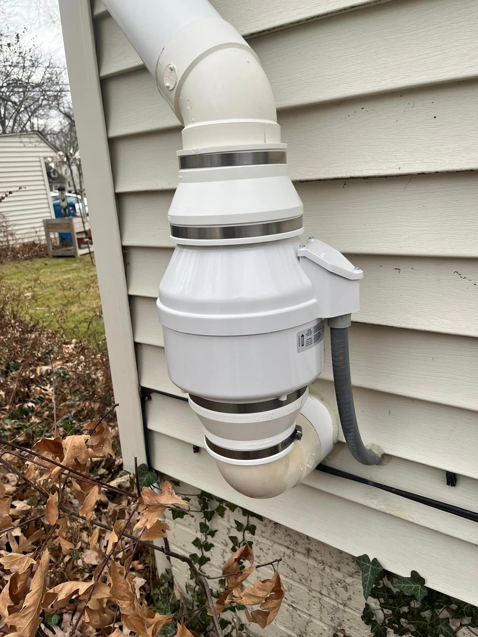 A white pipe is attached to the side of a house.