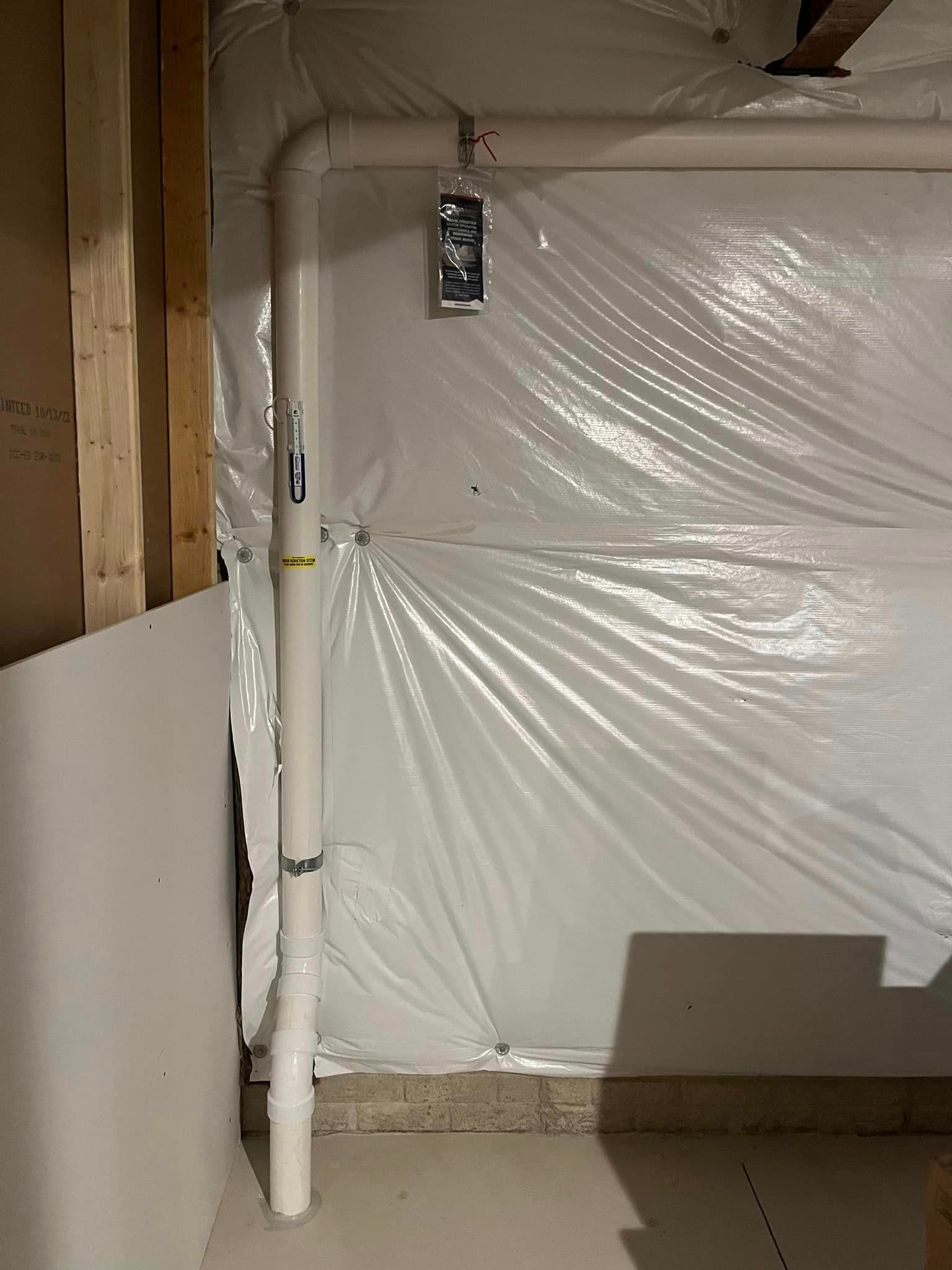 A white pipe is sitting in a room covered in plastic.