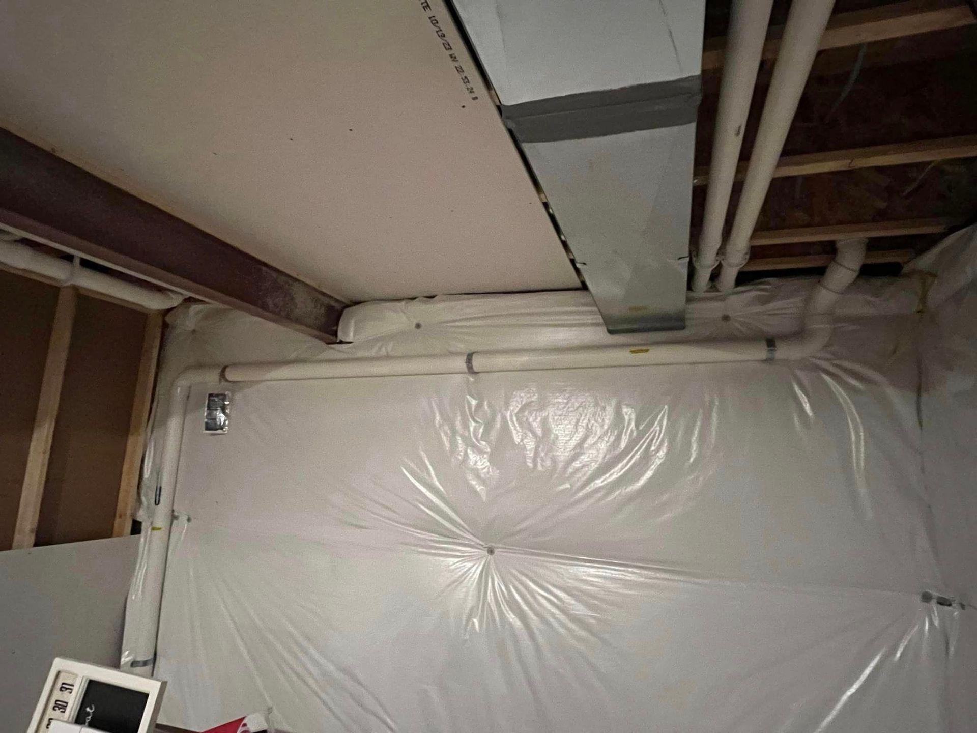 A basement with plastic covering the walls and ceiling.