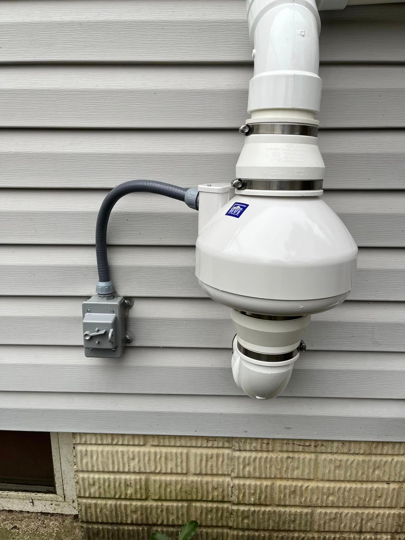 A white pipe is attached to the side of a house.
