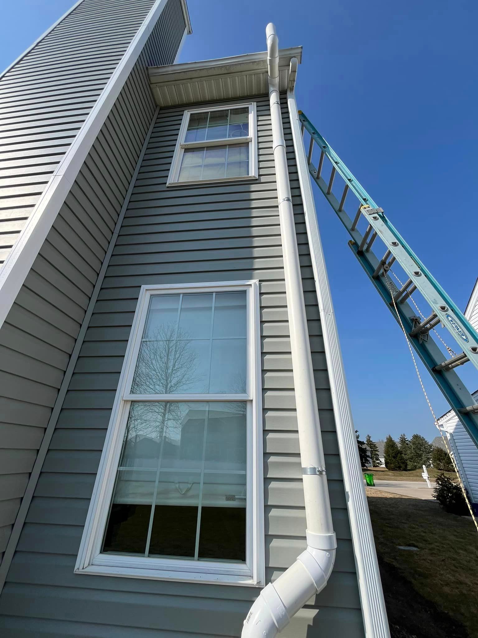 A ladder is hanging from the side of a building next to a window.