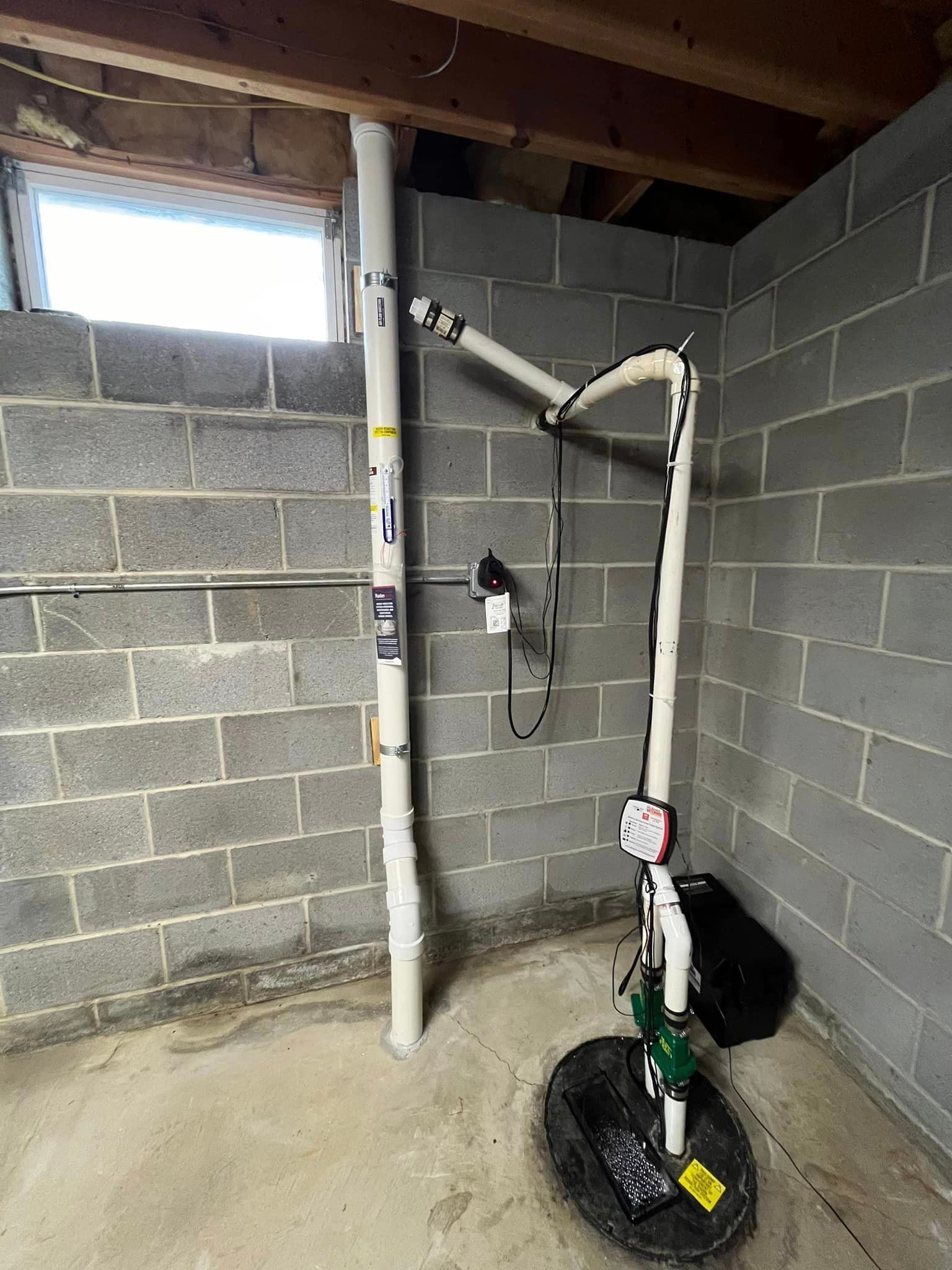 A basement with a drain pump and a window.