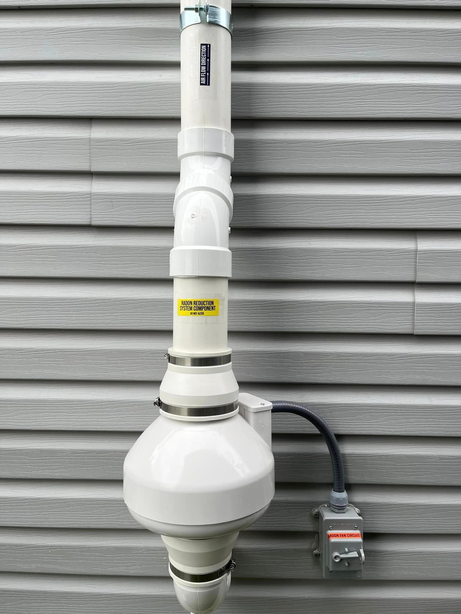 A white pipe is attached to the side of a building.