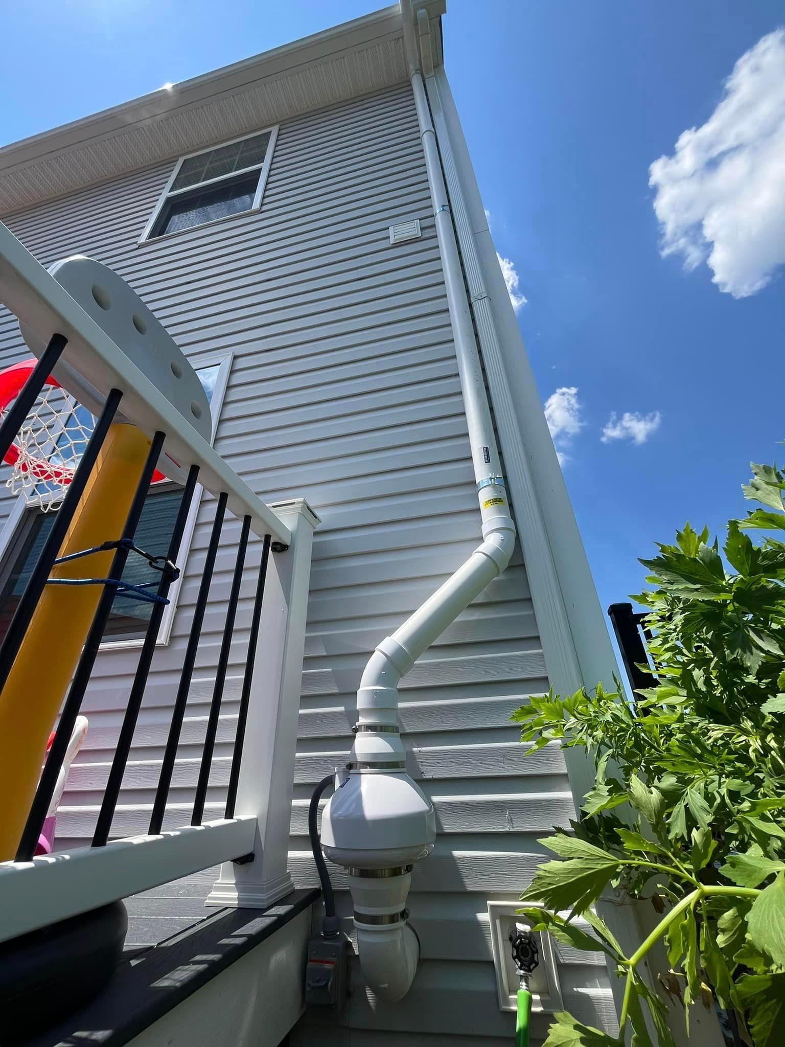 A white house with a drain pipe on the side of it.