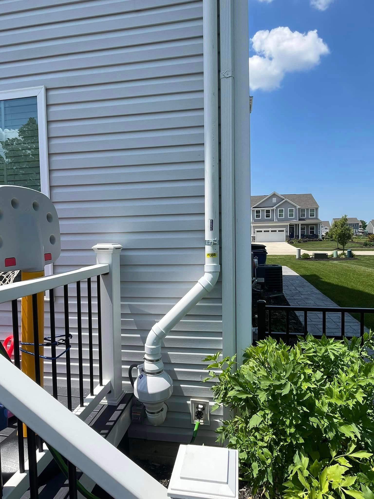 A white house with a drain pipe on the side of it.