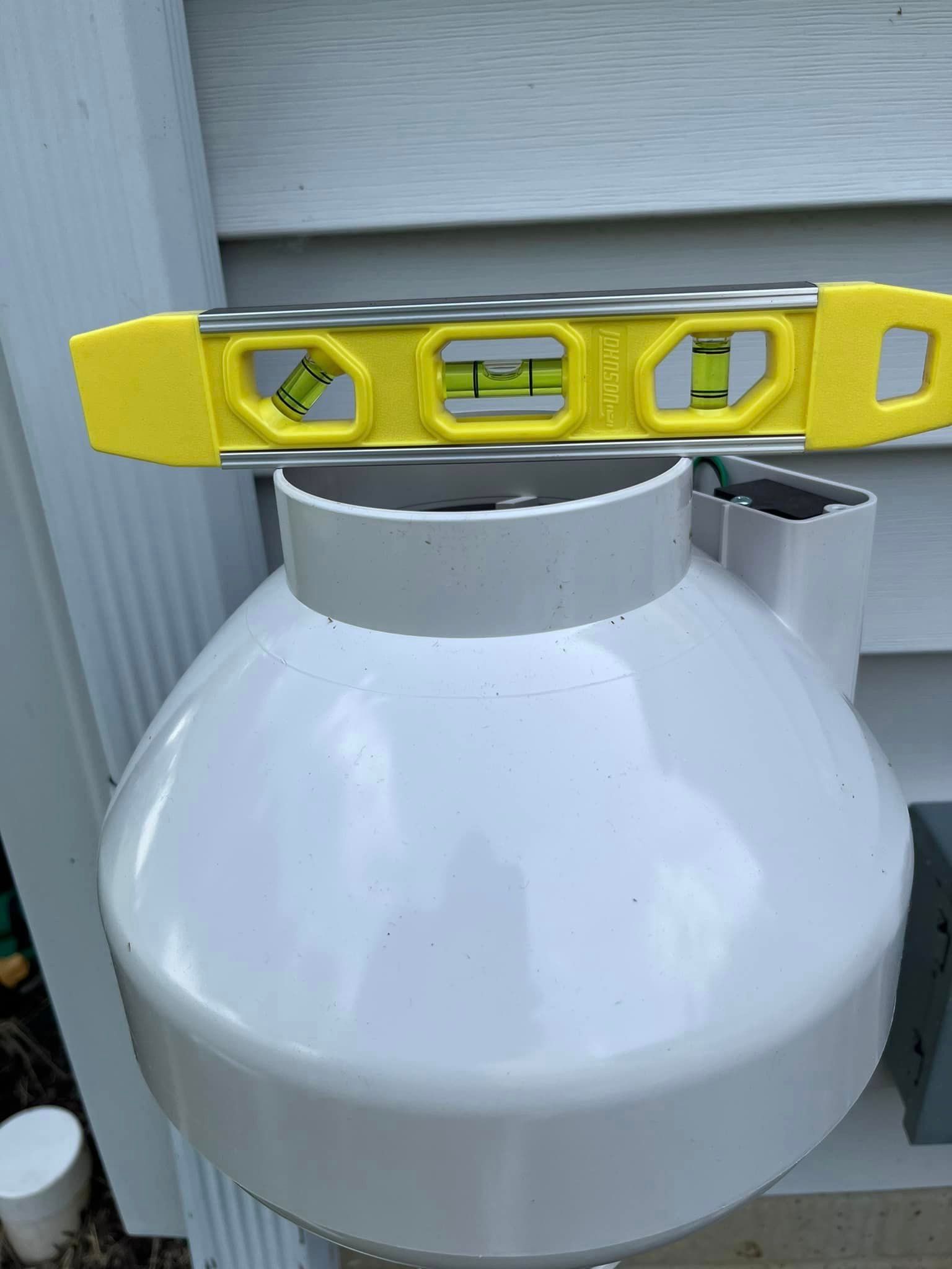A yellow level is sitting on top of a white propane tank.
