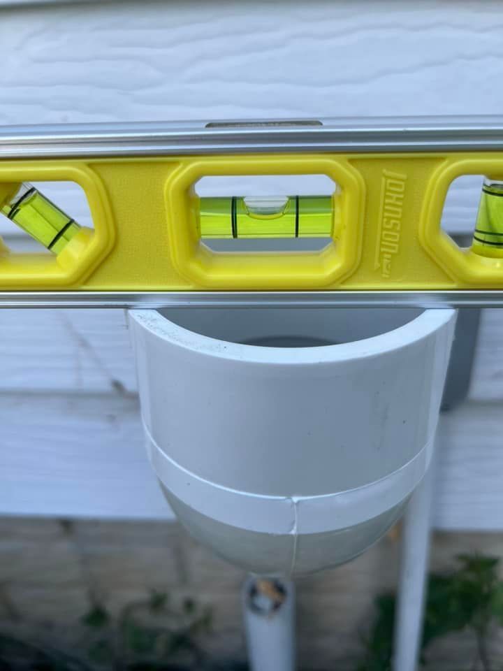 A yellow level is sitting on top of a white pipe.