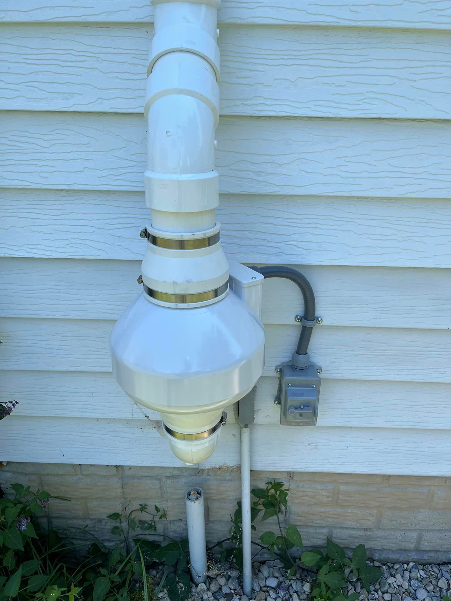 A white pipe is attached to the side of a house.