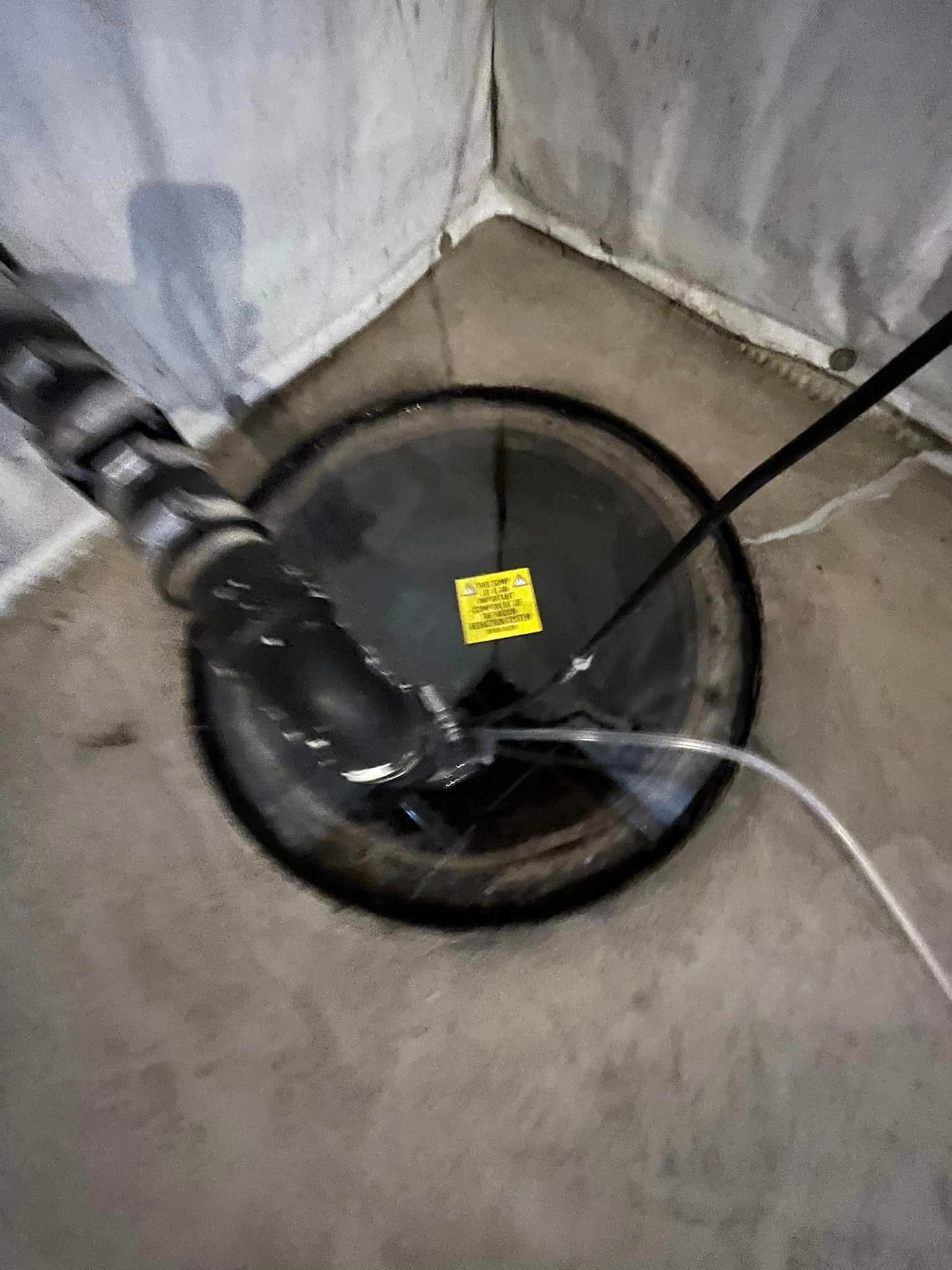 A drain in a basement with a hose coming out of it.