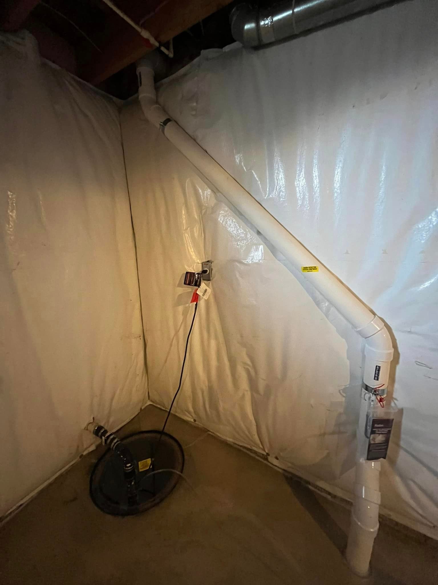 There is a drain in the corner of a basement.